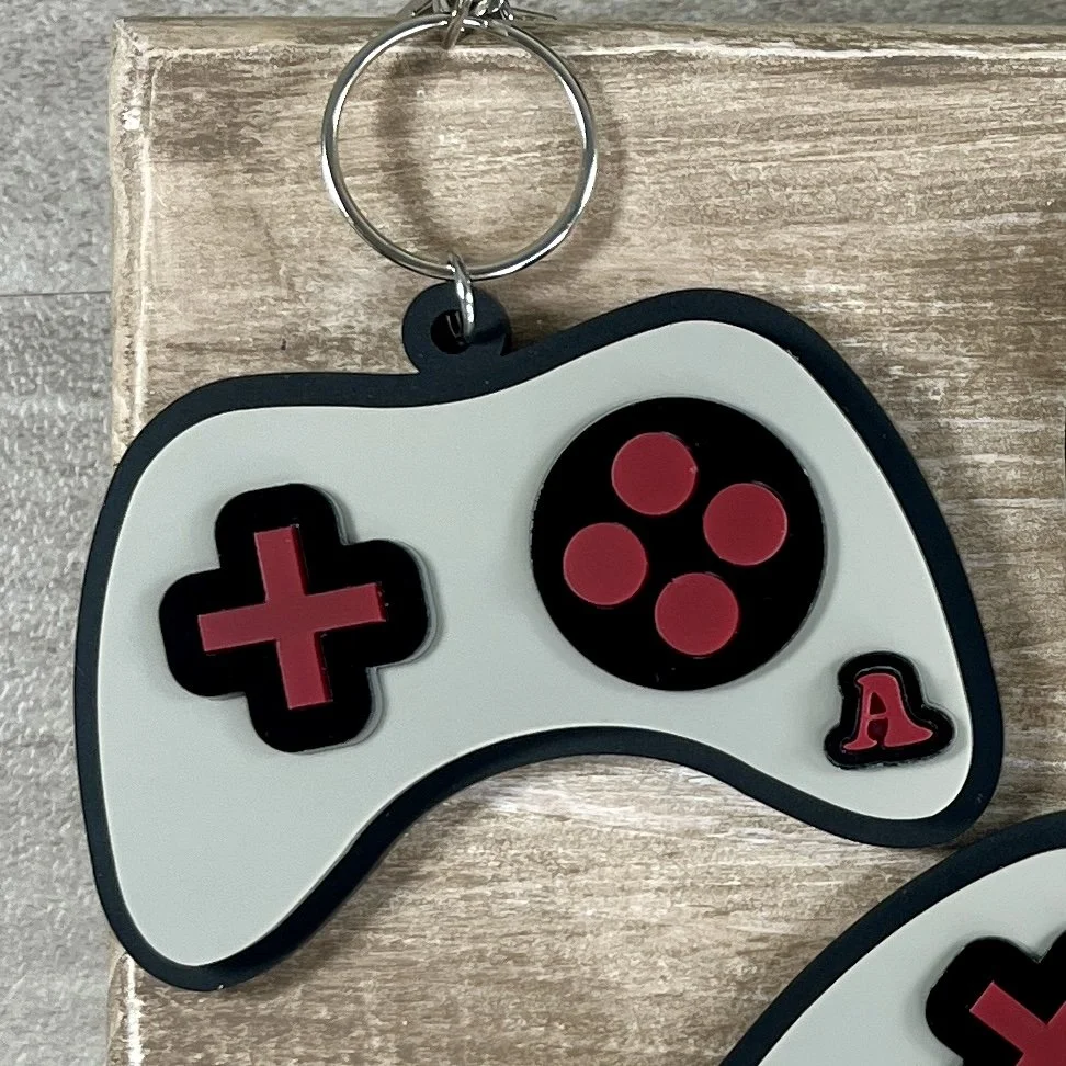 Close up of game controller-shaped acrylic backpack tag showing personalization.