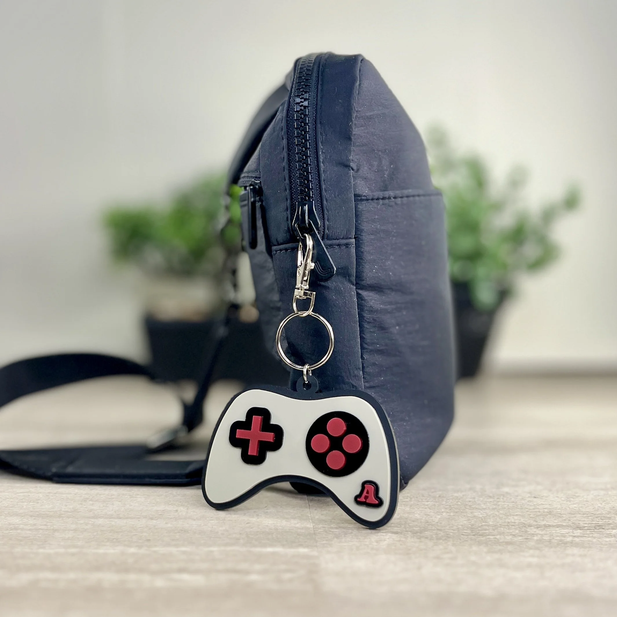 Game controller-shaped acrylic backpack tag in use, hanging from bag.