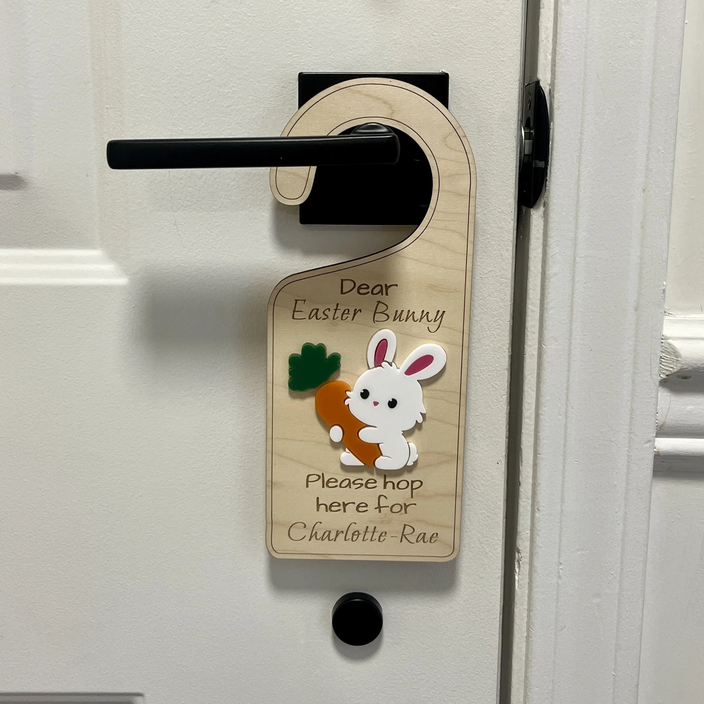 Laser cut maple wood Easter bunny door hanger with raised Easter bunny graphics hanging from a door knob.