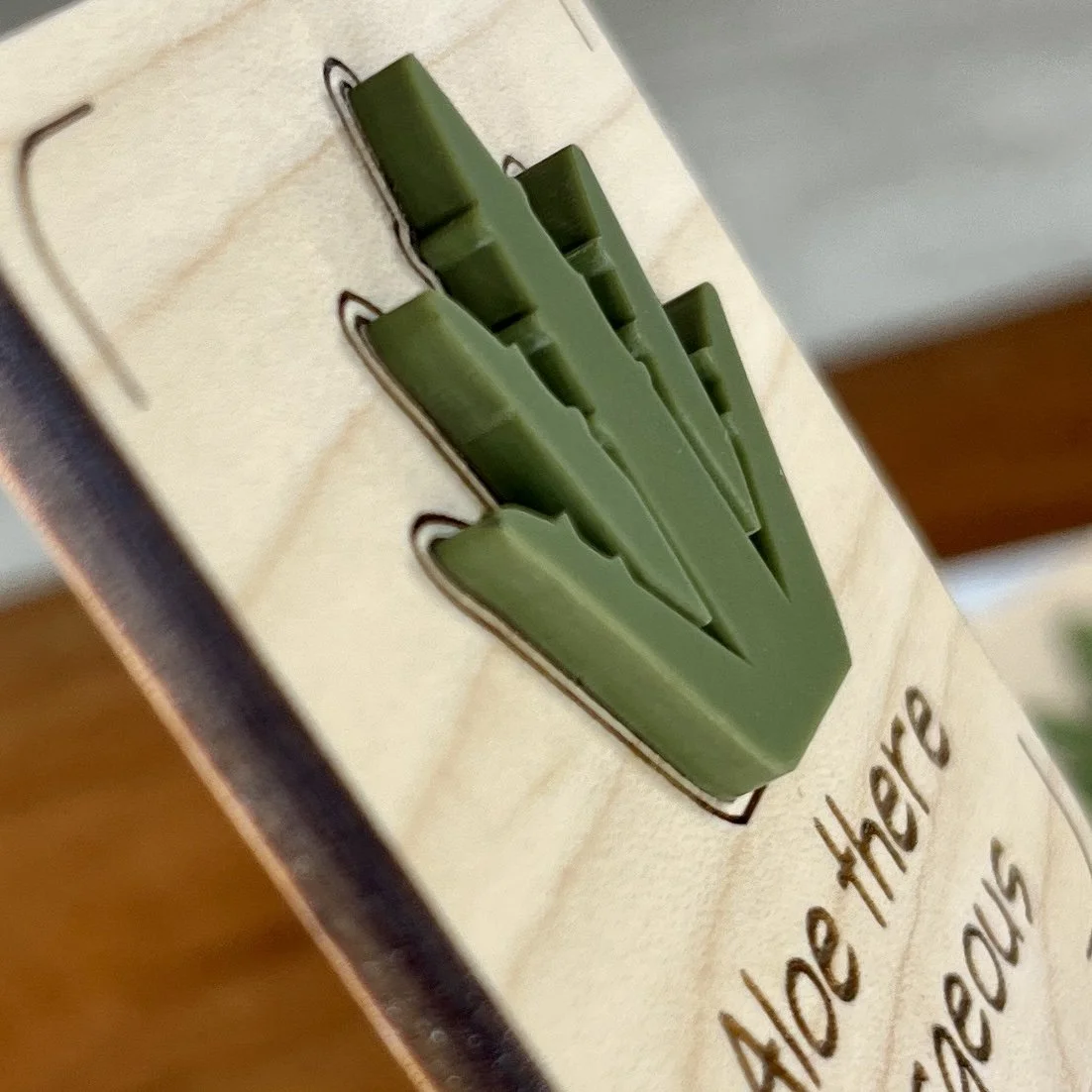 angled view maple plant stake featuring an acrylic aloe plant embellishment engraved with the phrase "Aloe there gorgeous".