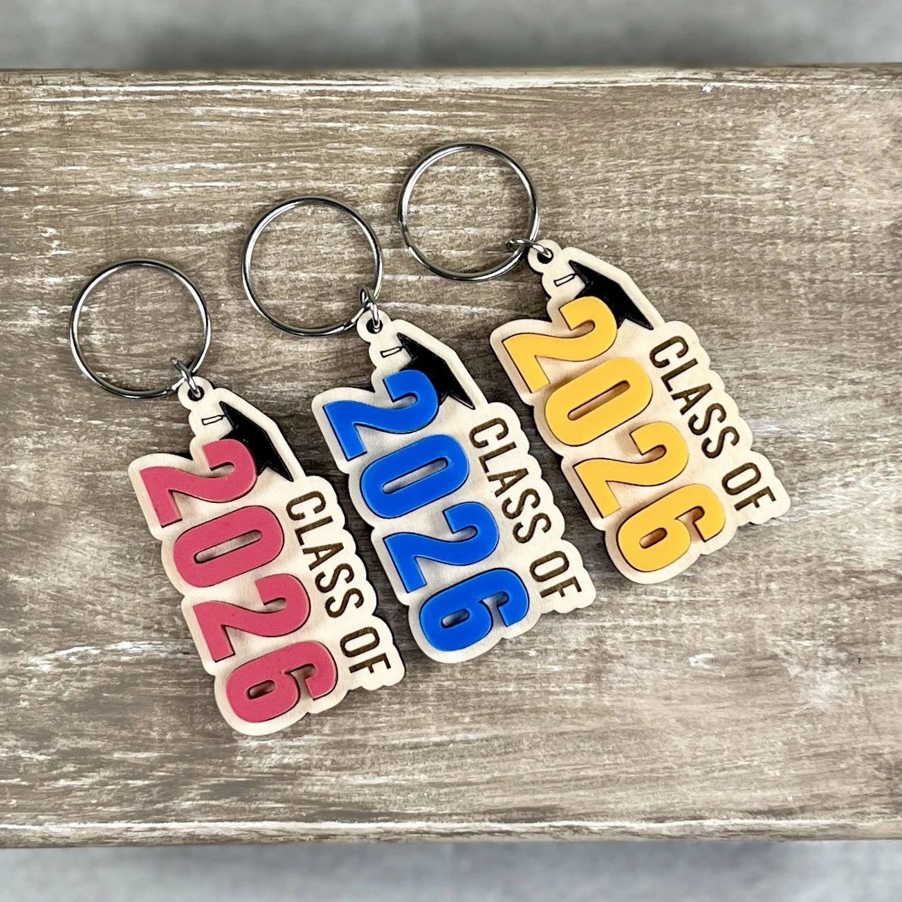 Front view of a Class Of graduation keychain showing raised matte acrylic numbers layered on engraved maple wood, highlighting depth and texture.