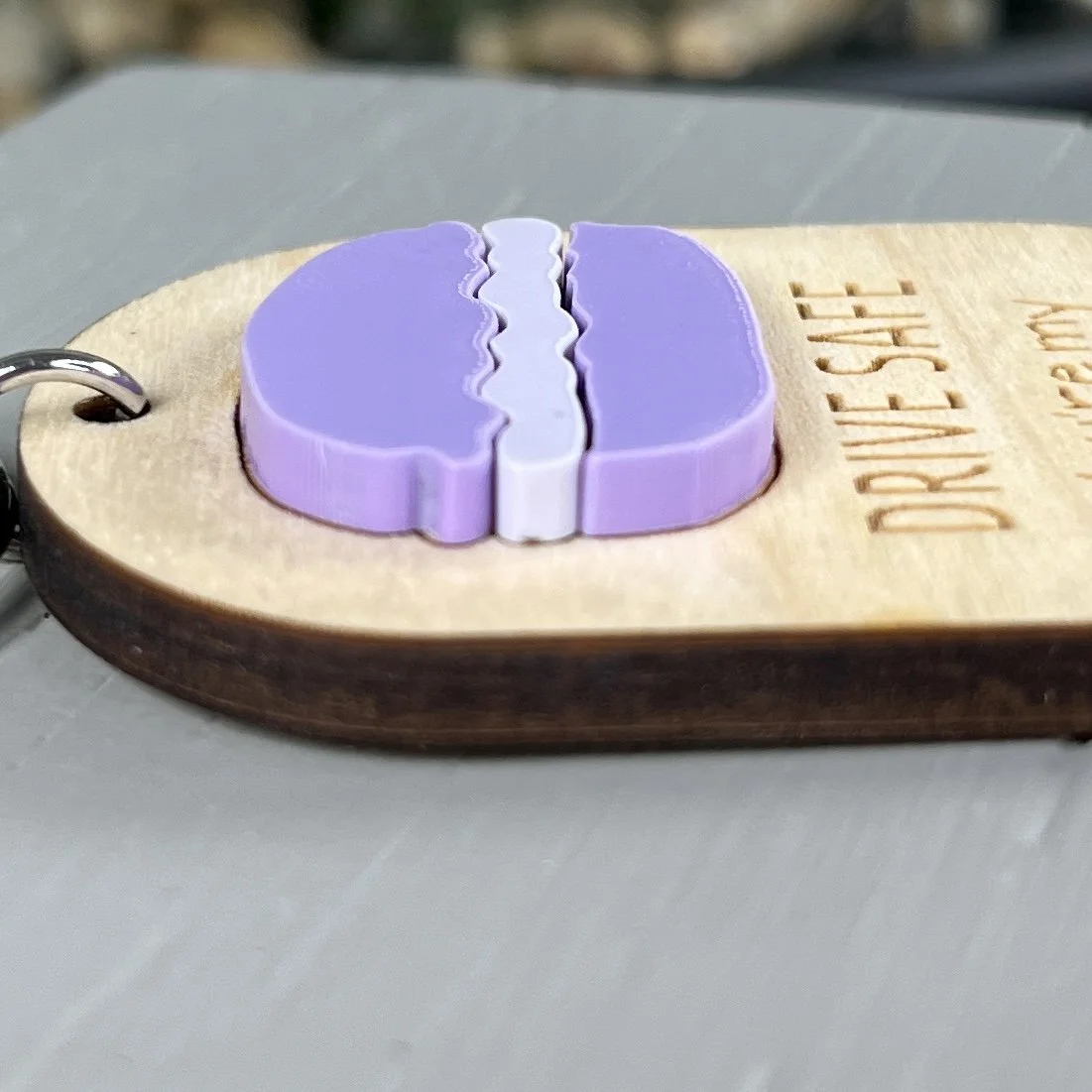 side view of laser cut maple wood keychain with macaron cookie in matte orchid/white matte acrylic highlighting the depth and texture of the product.