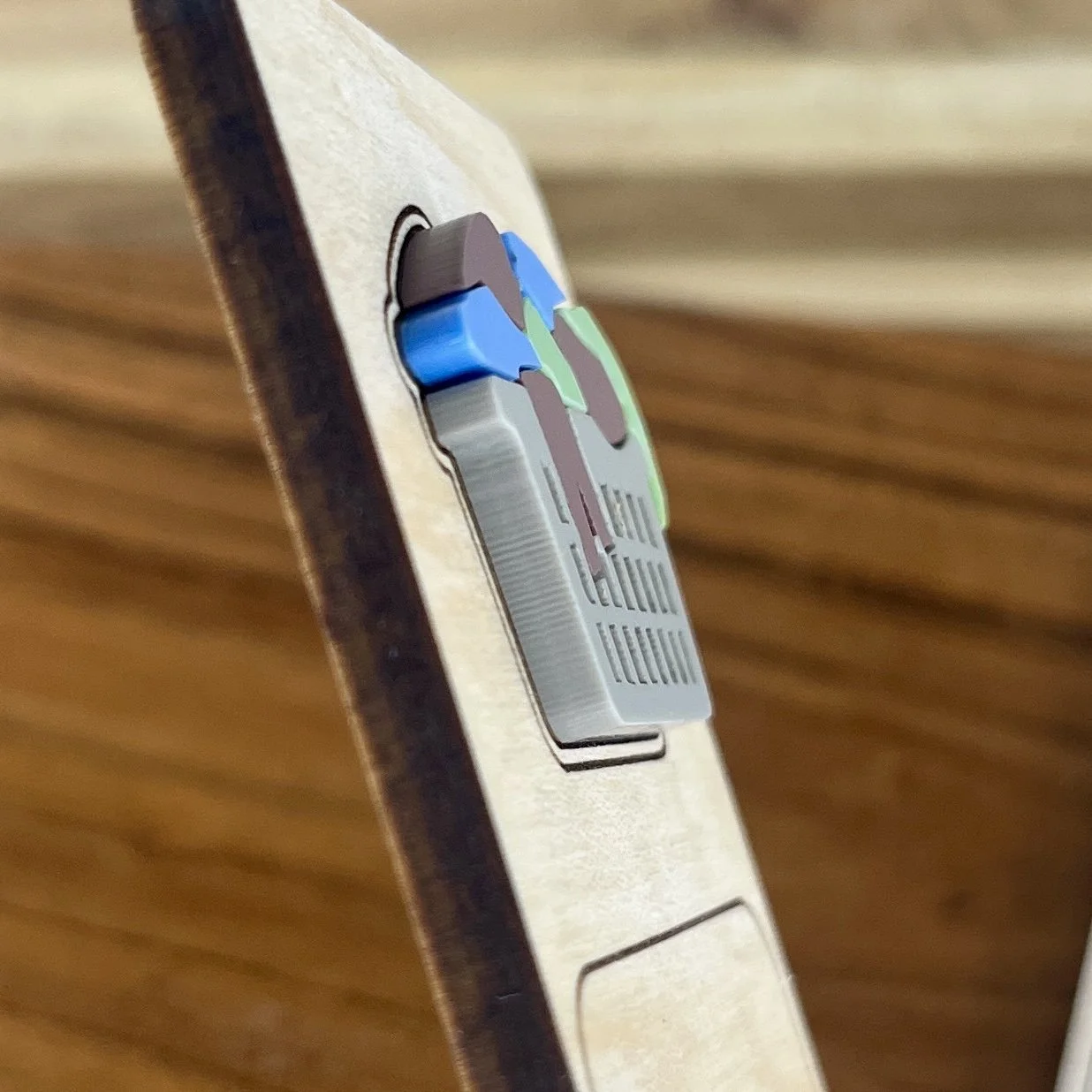 angled view maple bookmark featuring multi-coloured acrylic overflowing laundry basket embellishment engraved with the phrase "Current status: ignoring responsibilities".