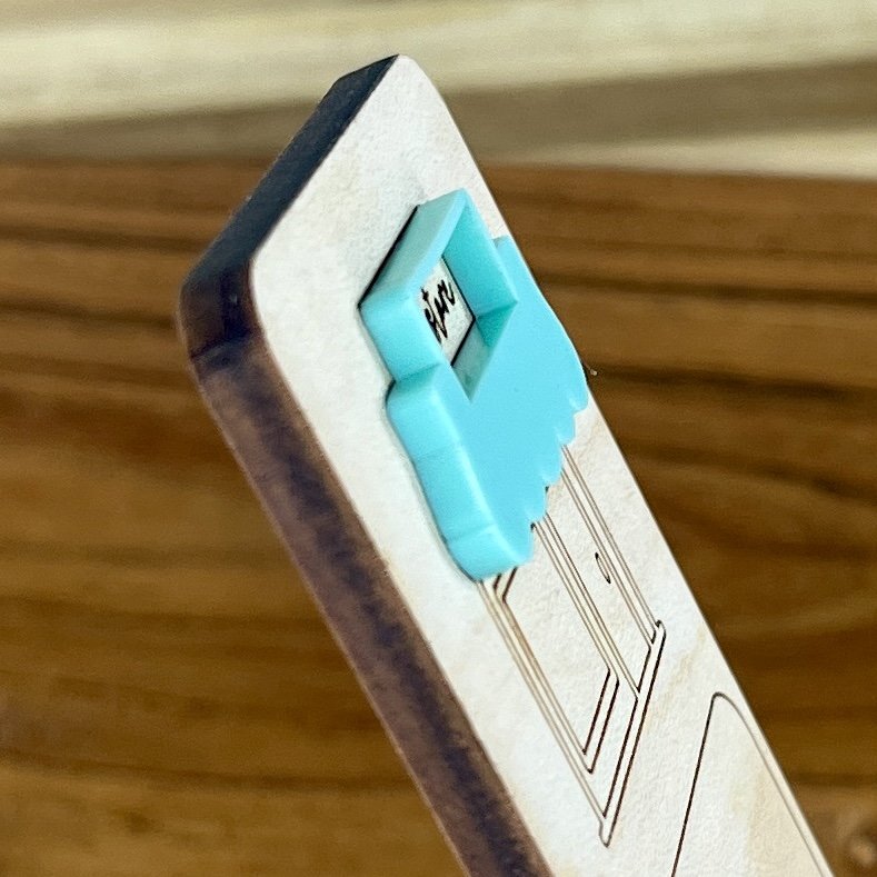 angled view maple bookmark featuring mint acrylic bookstore awning above a bookstore storefront illustration engraved with the phrase "I brake for bookstores".