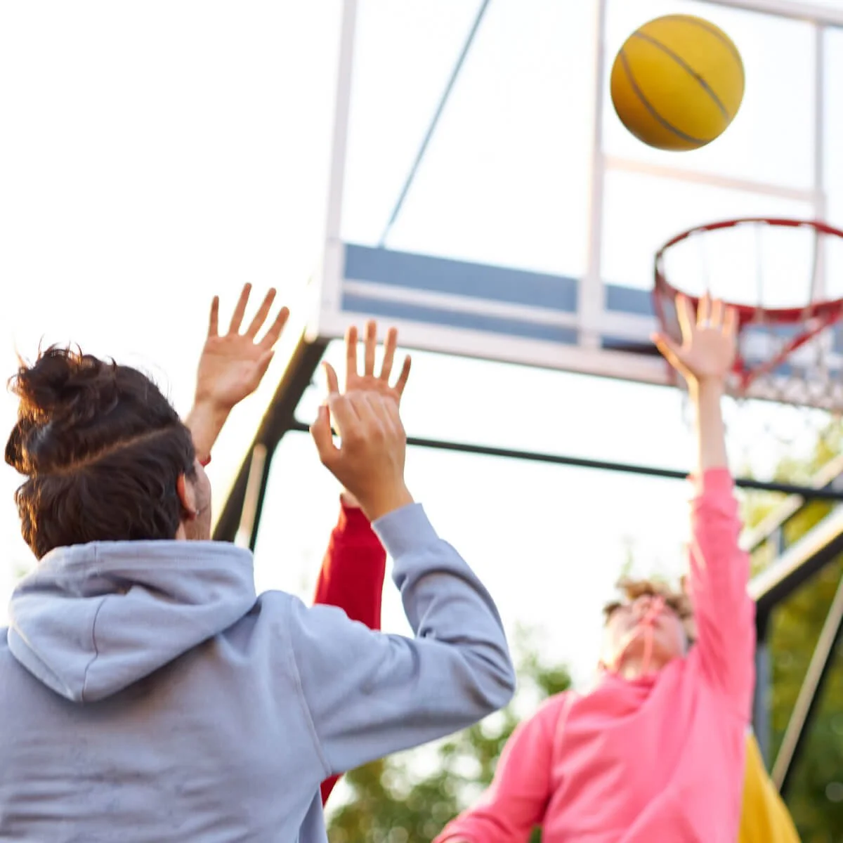 Teens playing basketball outdoors in community setting, illustrating fundraising events that engage students and supporters.