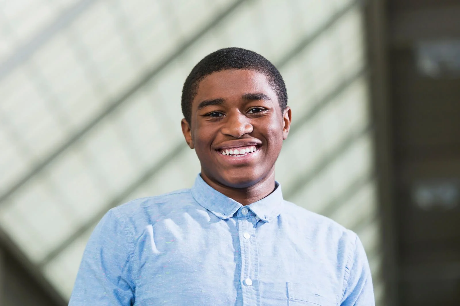Confident student in a button-up shirt standing in a professional environment, representing Grace Place School’s business development program and entrepreneurship training.