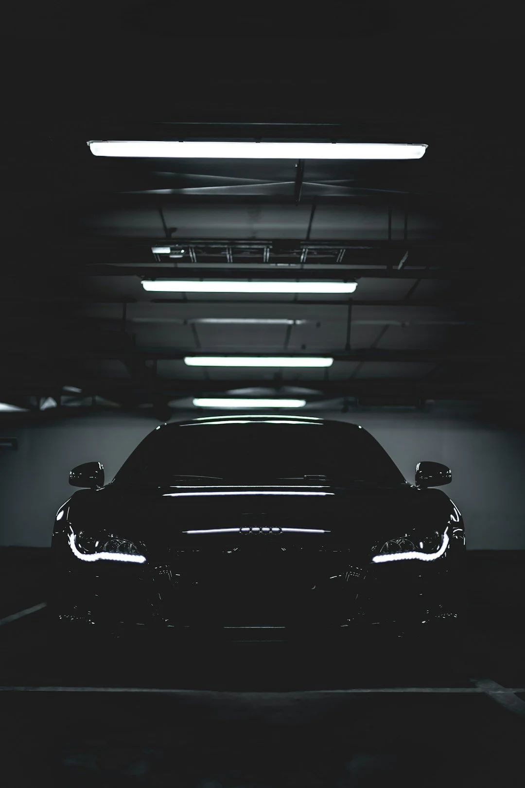 Luxury car with illuminated headlights in a dark underground parking garage
