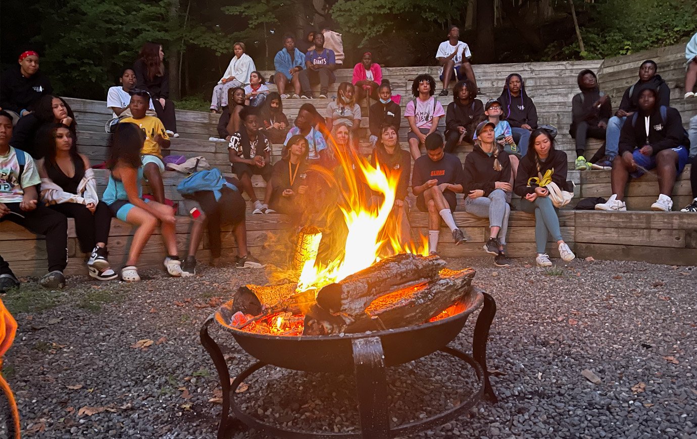 Teens sitting by the campfire at dusk