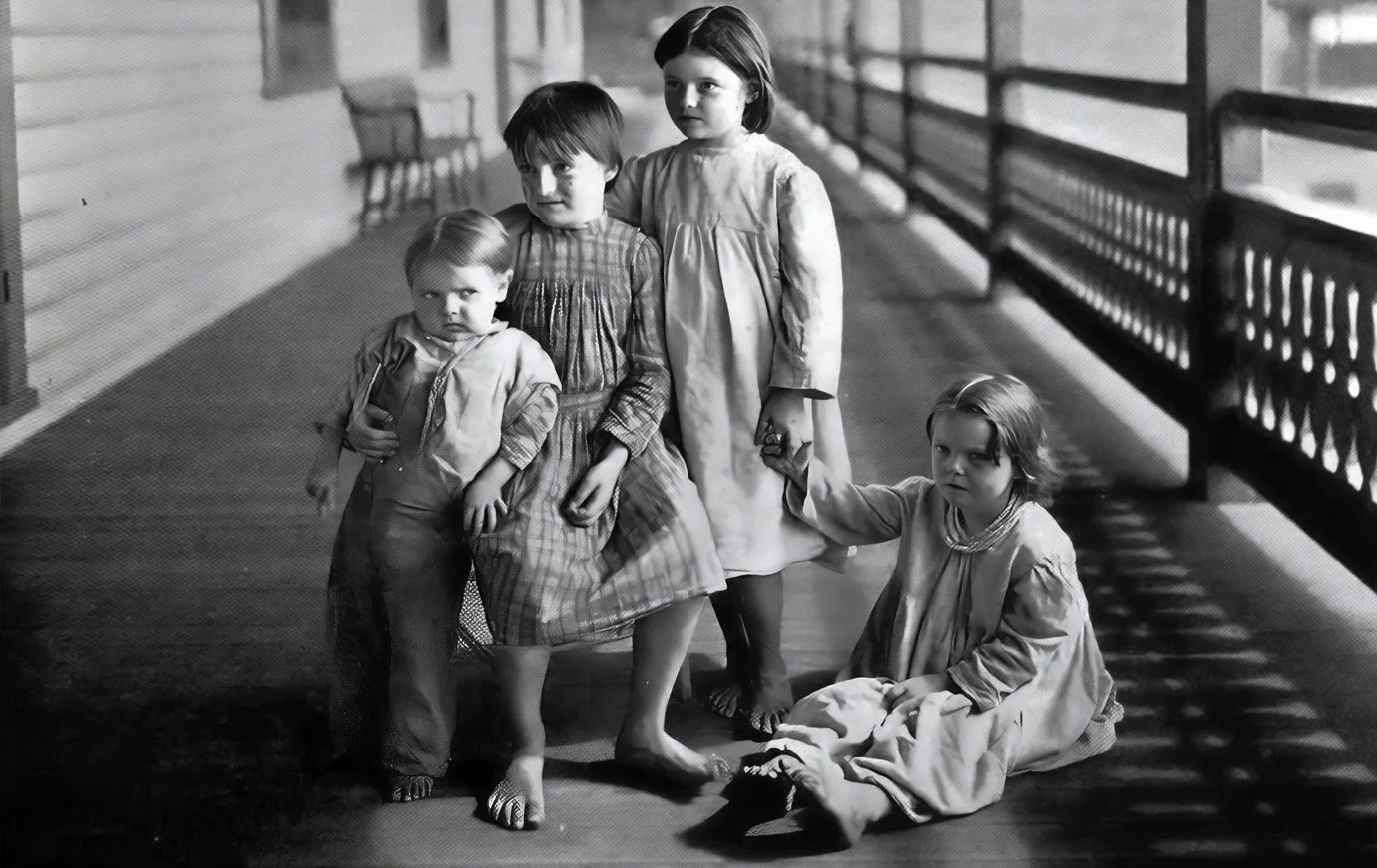 A "little mother" and siblings on the verandah at Seaside Hospital.