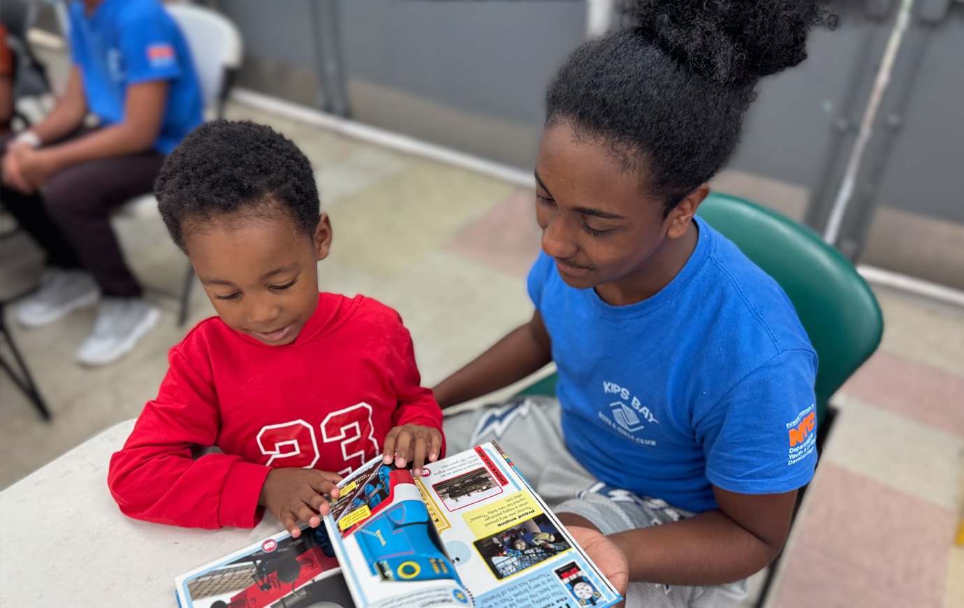 A volunteer reads about Thomas the Tank to a small boy