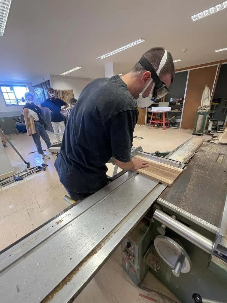 Participant cutting wood on a cabinet saw during a ManMade workshop