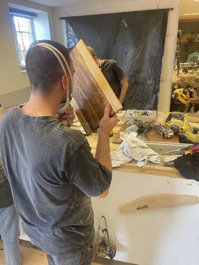 Dito pelo ChatGPT:

Participant inspecting a woodworking project during a ManMade workshop