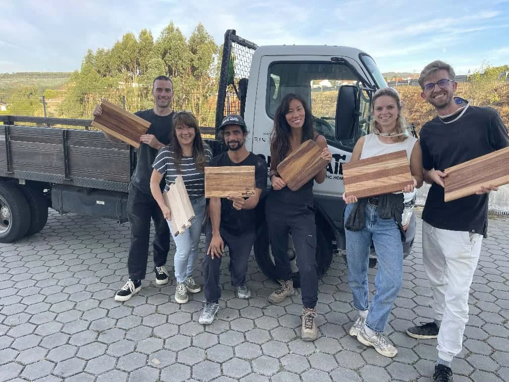 Group of participants holding finished cutting boards after a ManMade workshop outside the studio