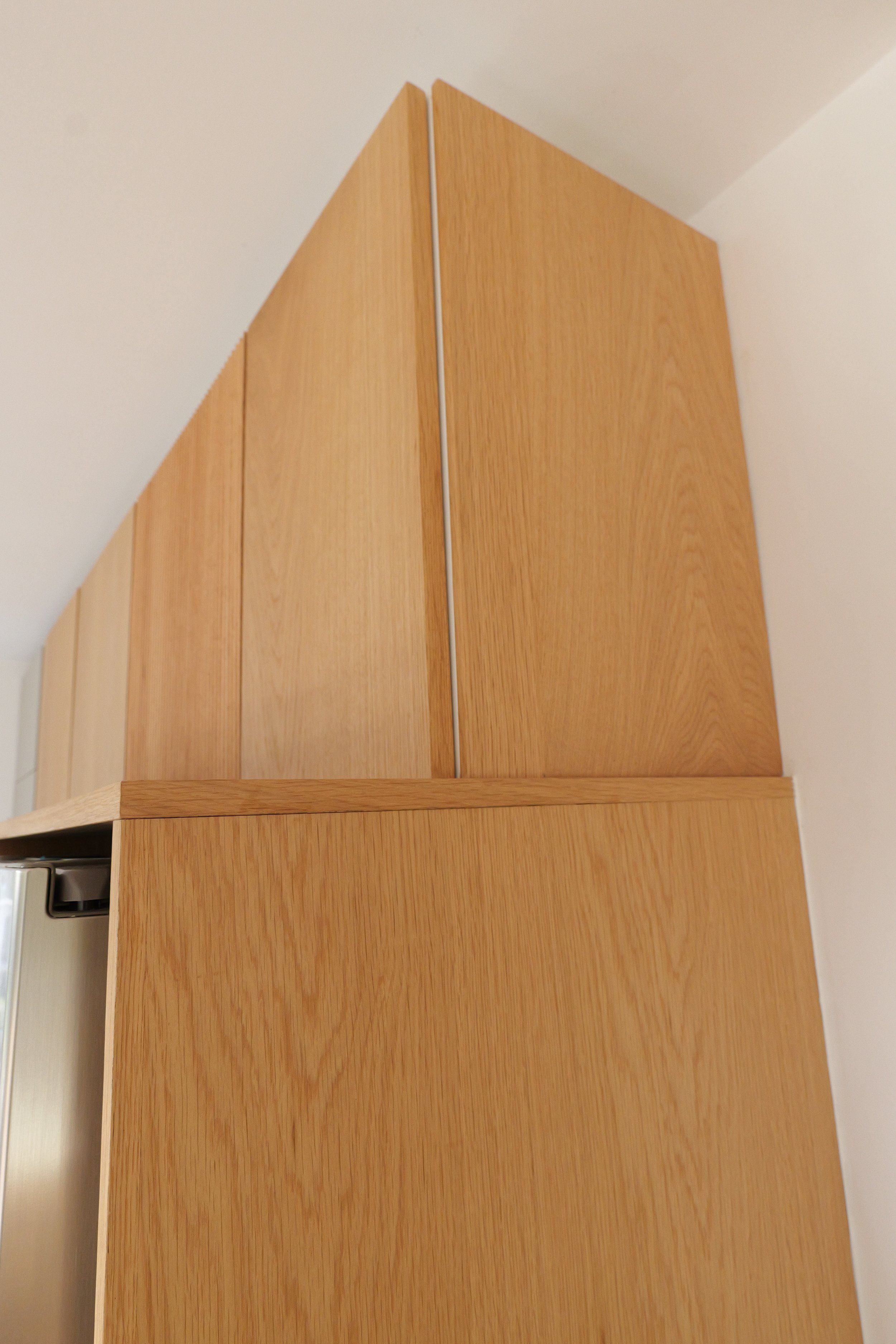 Custom oak paneling with Osmo oil fitted to IKEA cabinets, installed by ManMade in a client’s home.