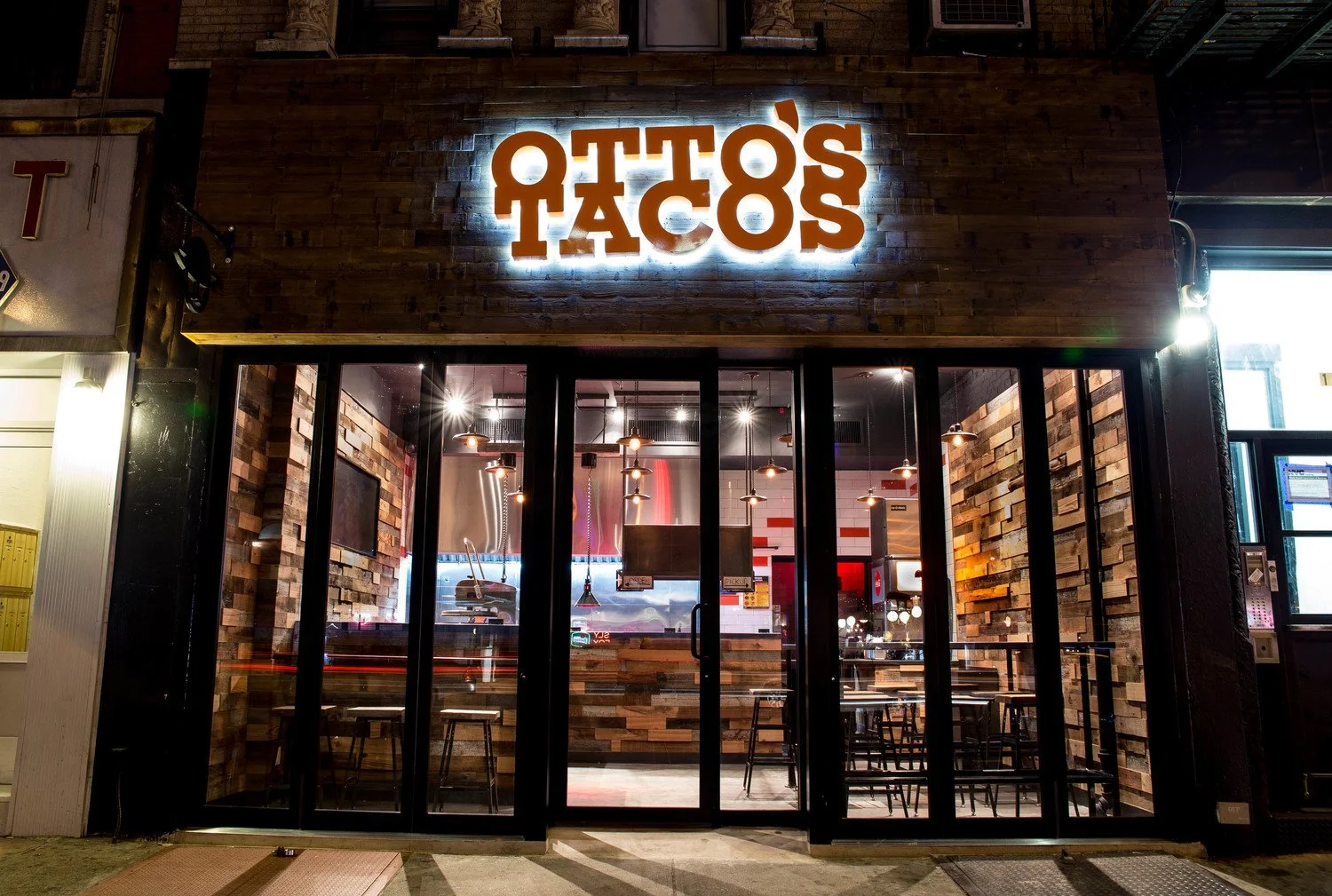 Exterior of Otto's Tacos restaurant at night with illuminated sign and wooden facade.