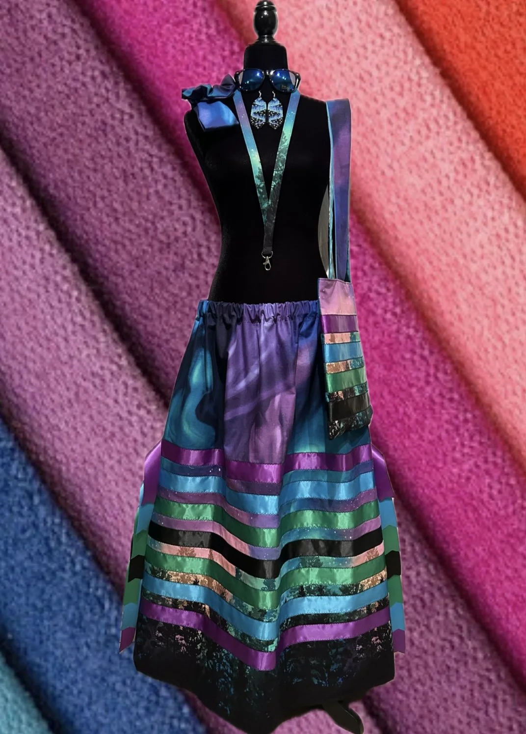 A mannequin wearing colorful accessories on a pink and purple textured background.