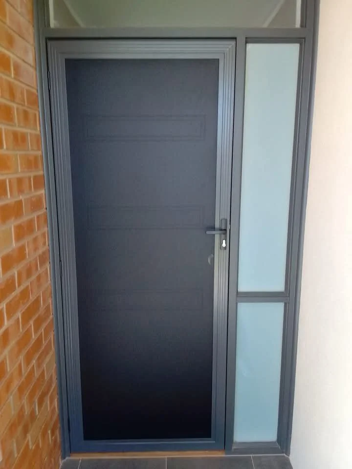 Black front door with glass side panels beside a brick wall.