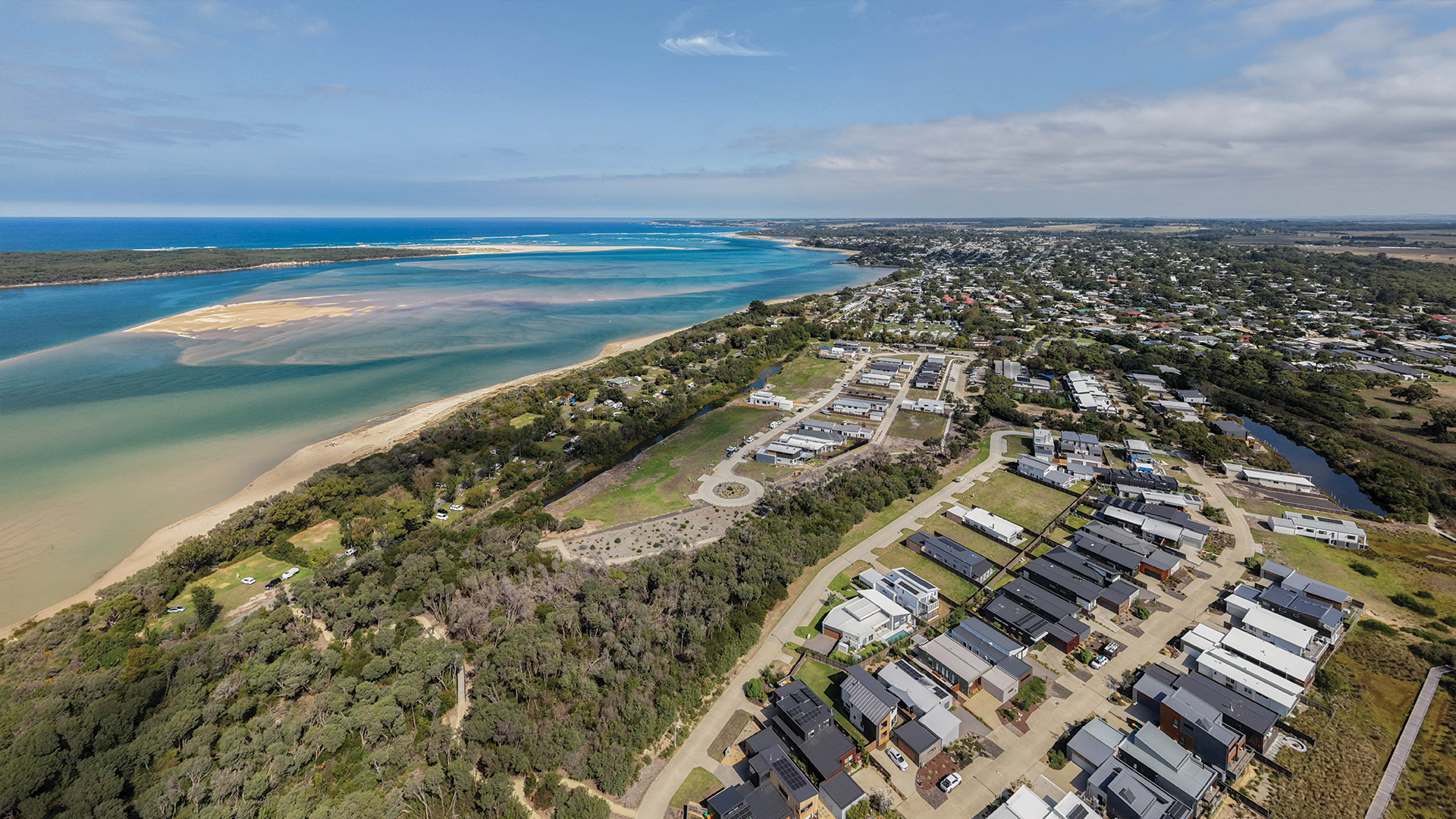 Aerial view of coastal town with beach, water, and residential area