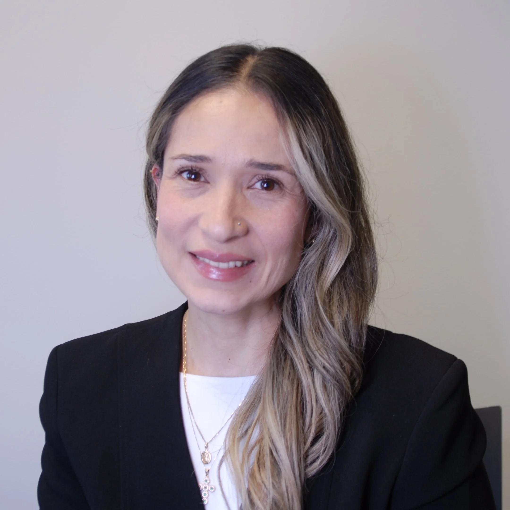 AlignWorks Solutions Admin & Technician support Deisi Chia. A woman with light skin, long wavy hair with blonde highlights, wearing a black blazer over a white top, smiling at the camera with a plain light-colored background.