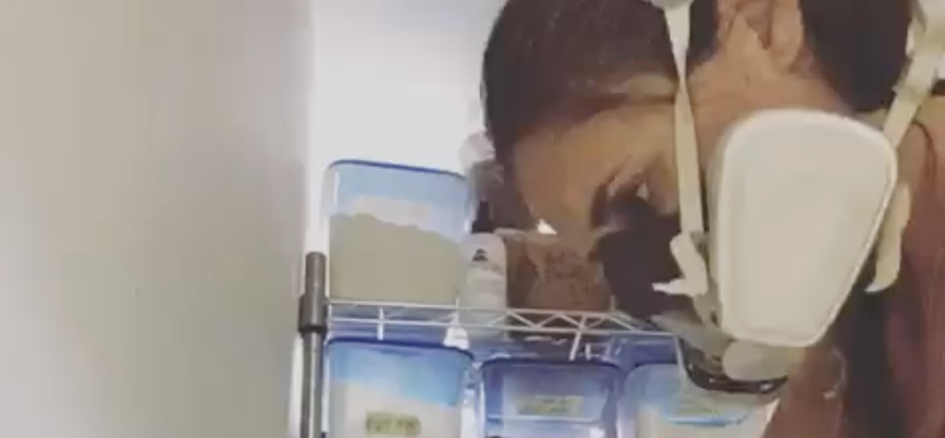 Sarah Stevens mixing glazes with an N95 mask on.