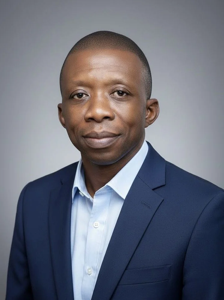 A young man with short hair, wearing navy blue jacket, smiling at the camera. Dan Tedzi, ghanaian fashion designer and tailor.