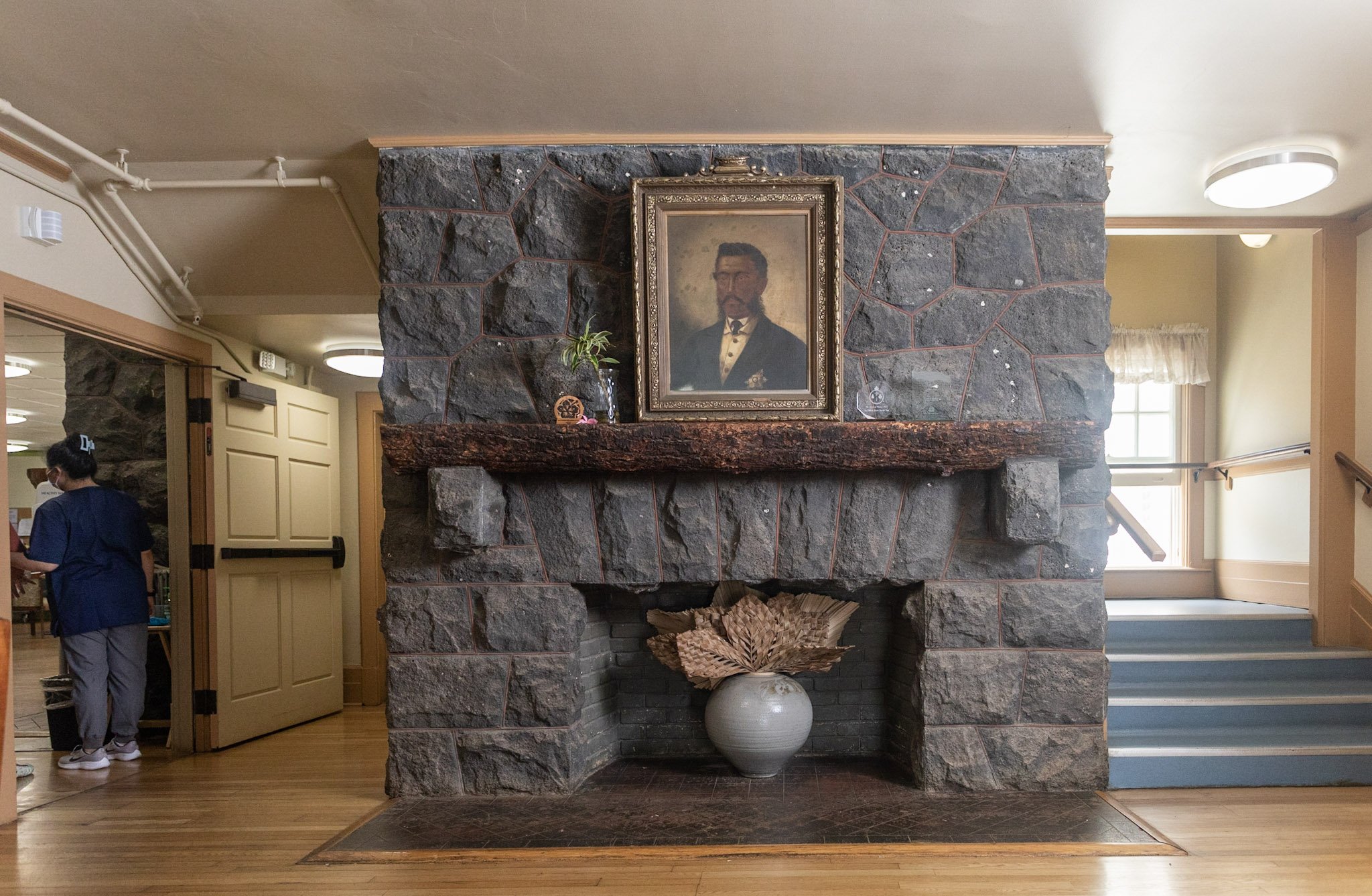 Framed portrait of King Lunalilo atop of a stone fireplace within the Lunalilo Home