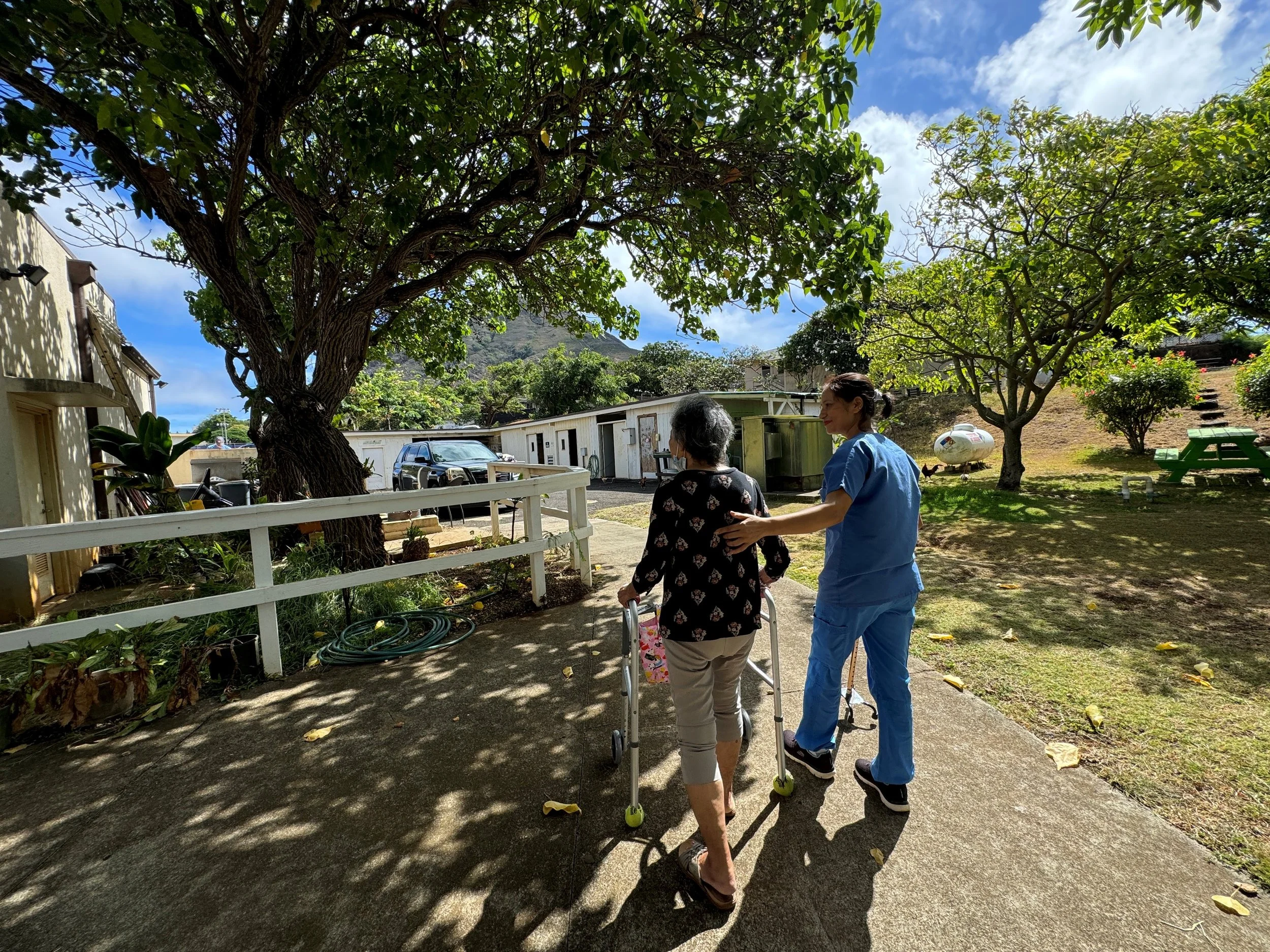 Nurse of the Lunalilo Home stabilizing resident kūpuna with a walker