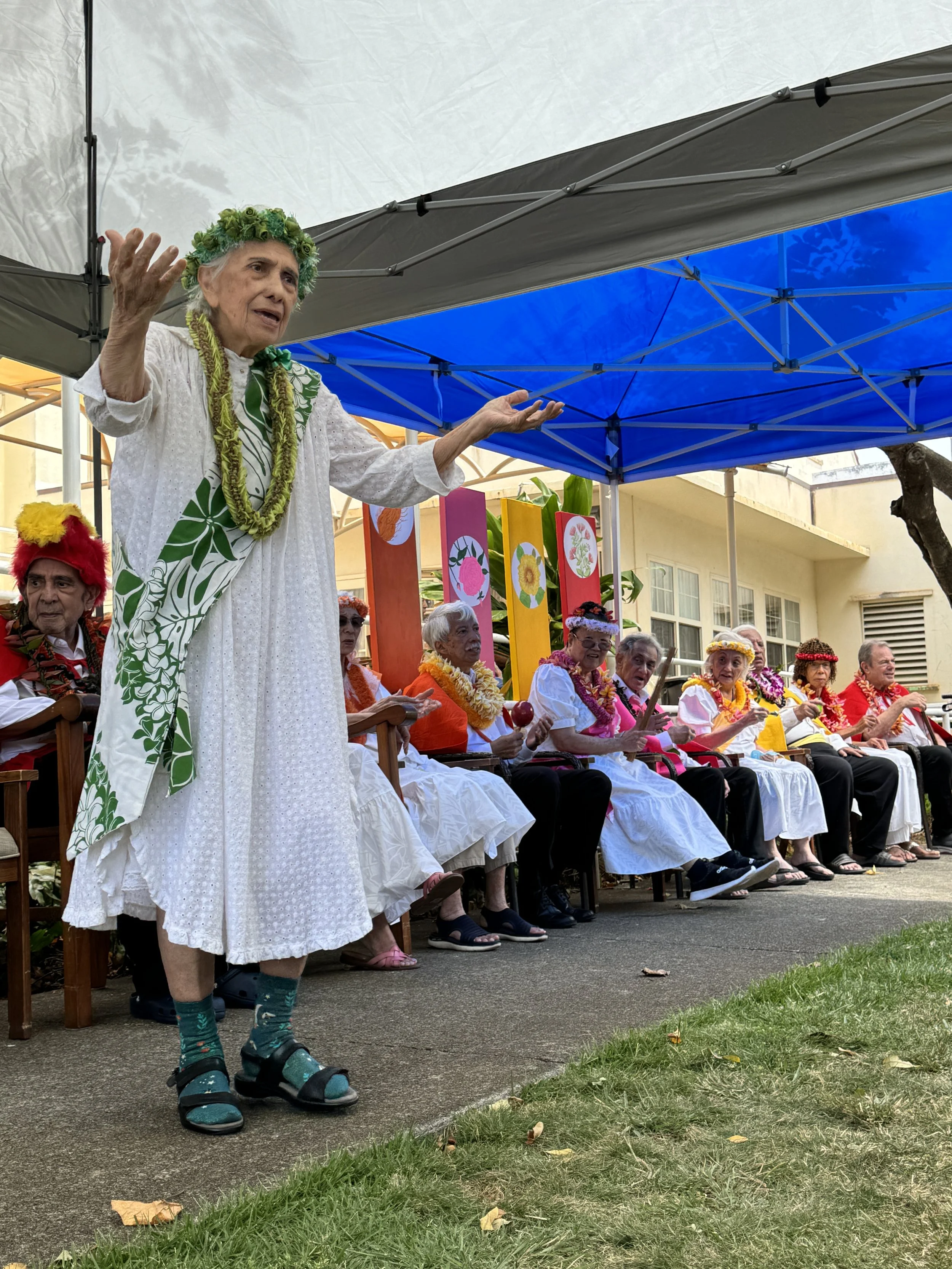 Kūpuna performing during a May Day celebration, with other kūpuna dressed as Kings and Queens of the Hawaiian Islands