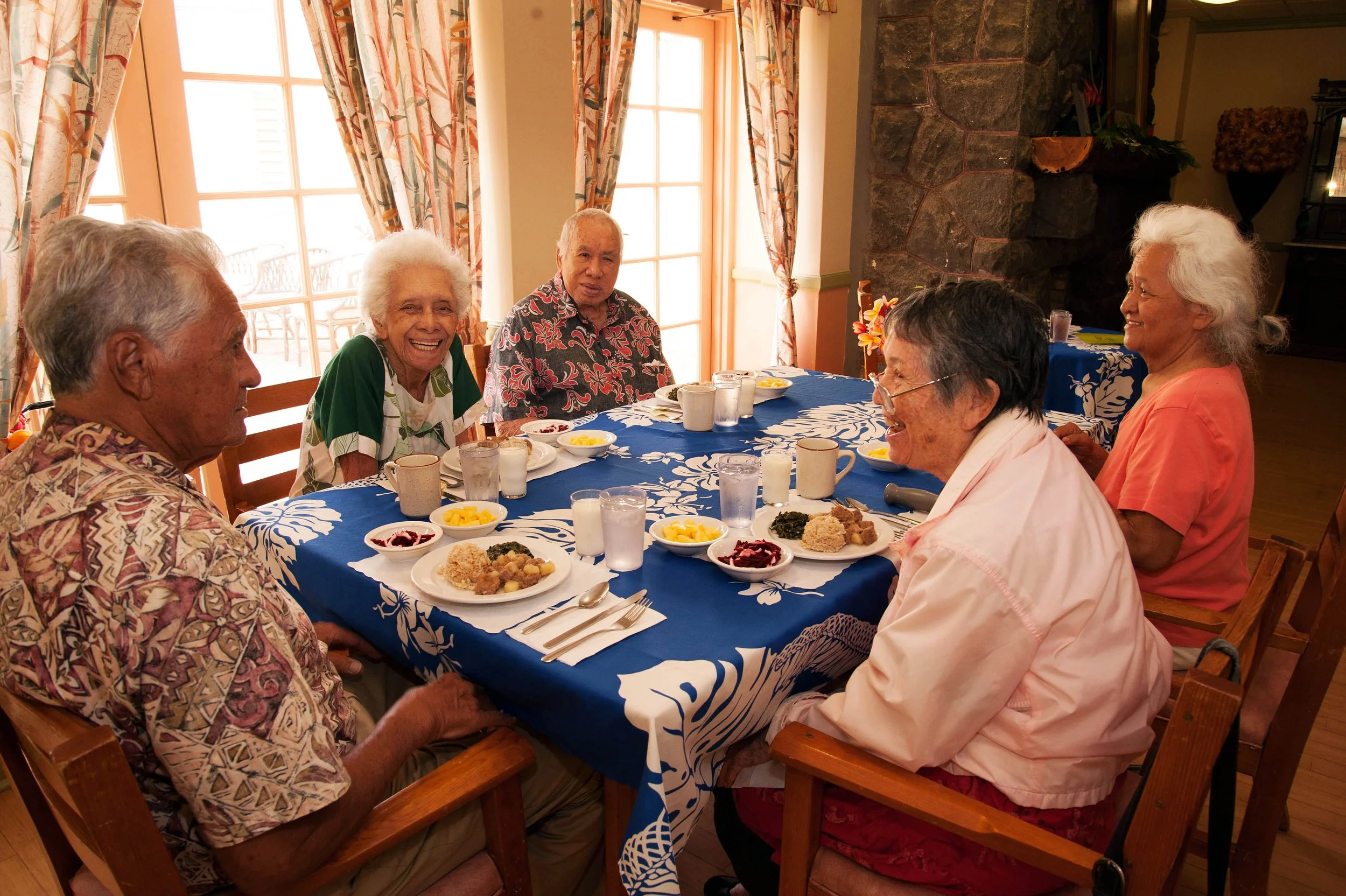 Joyous kūpuna at the dinner table laughing during lunch time 
