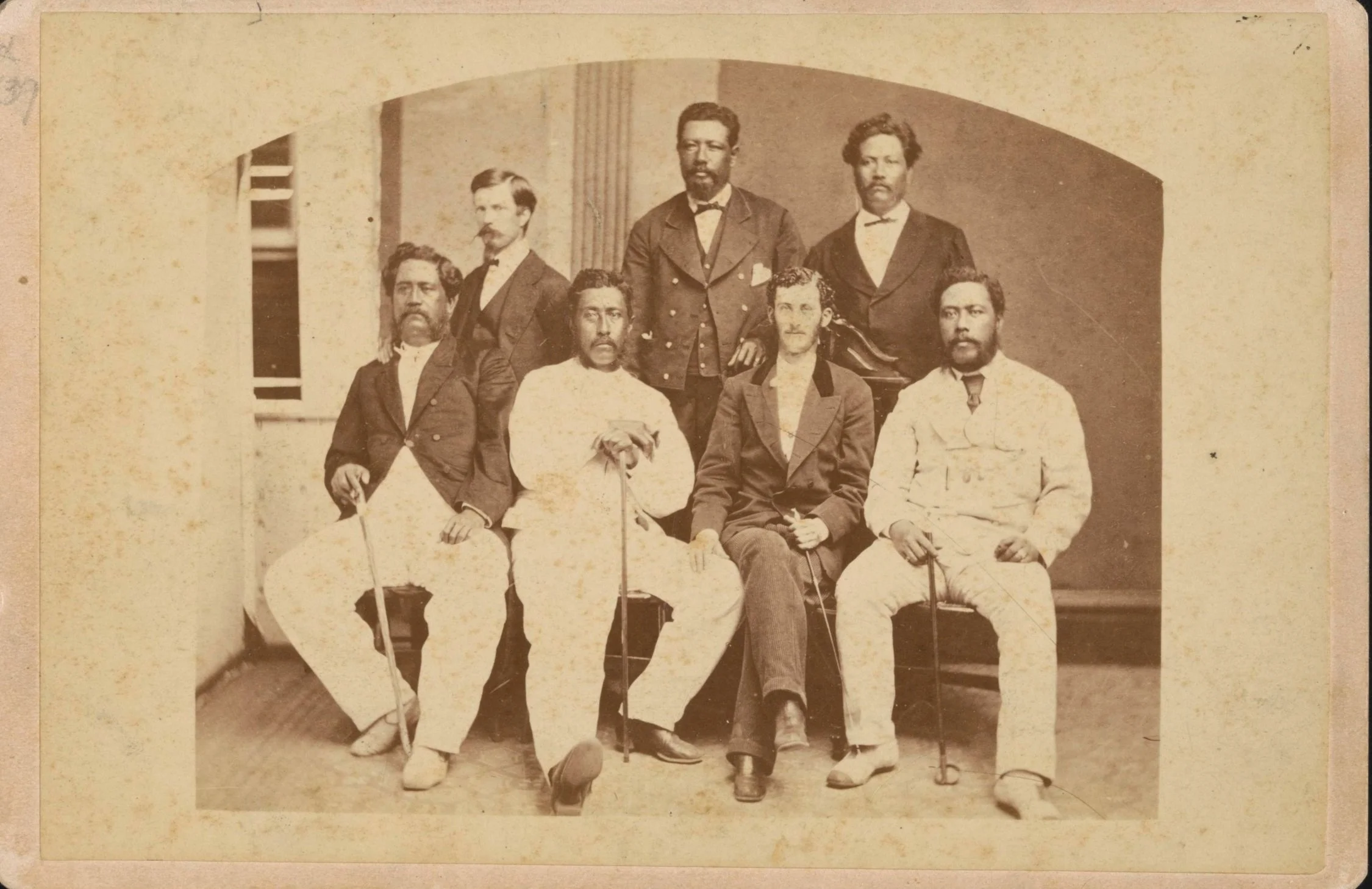 Historical photo of King Lunalilo seated with other historical figures: Kalākaua,  Dave McKinley, Charles W. Stoddard, and more.