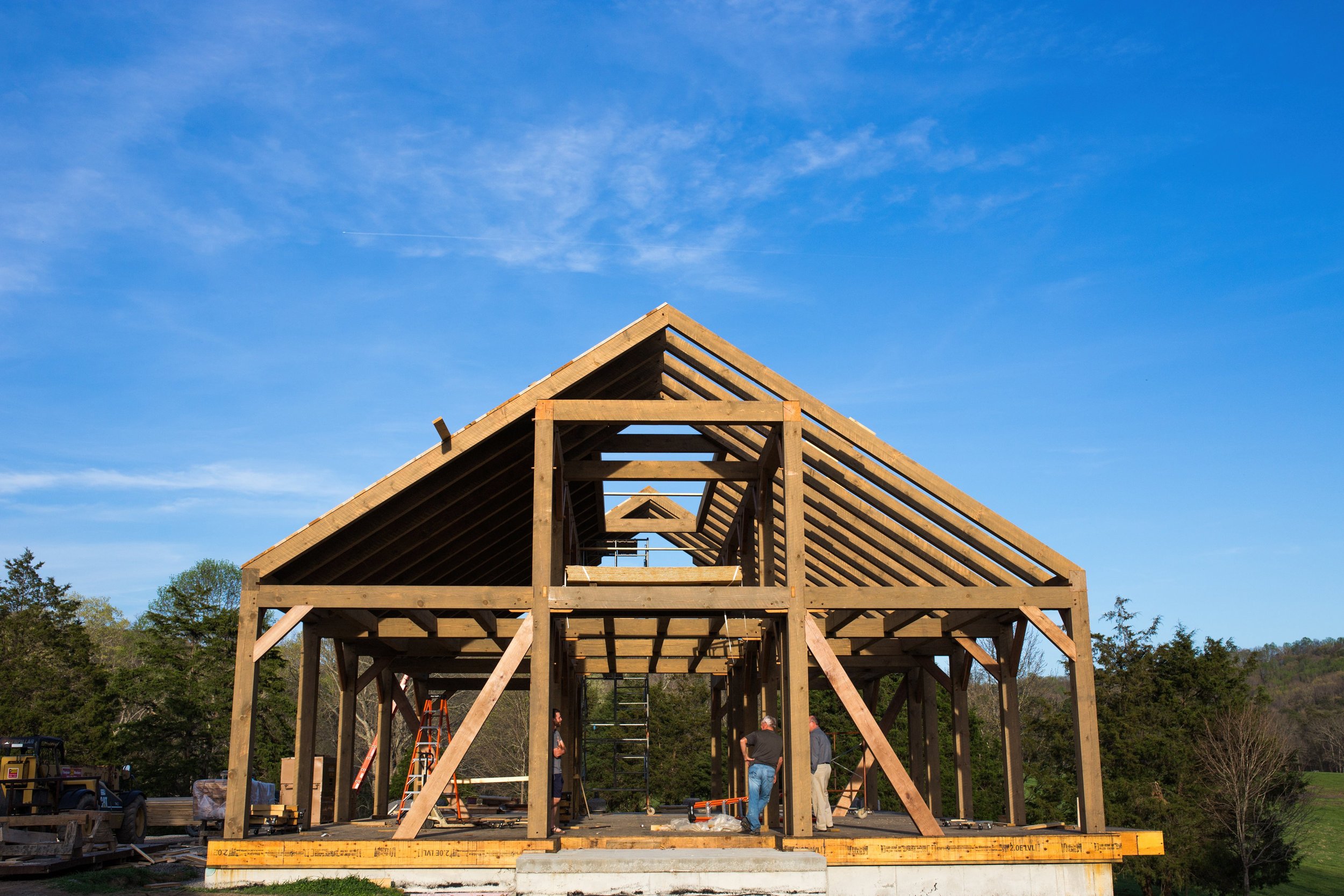 Construction workers building the wooden framework of a house on a sunny day.