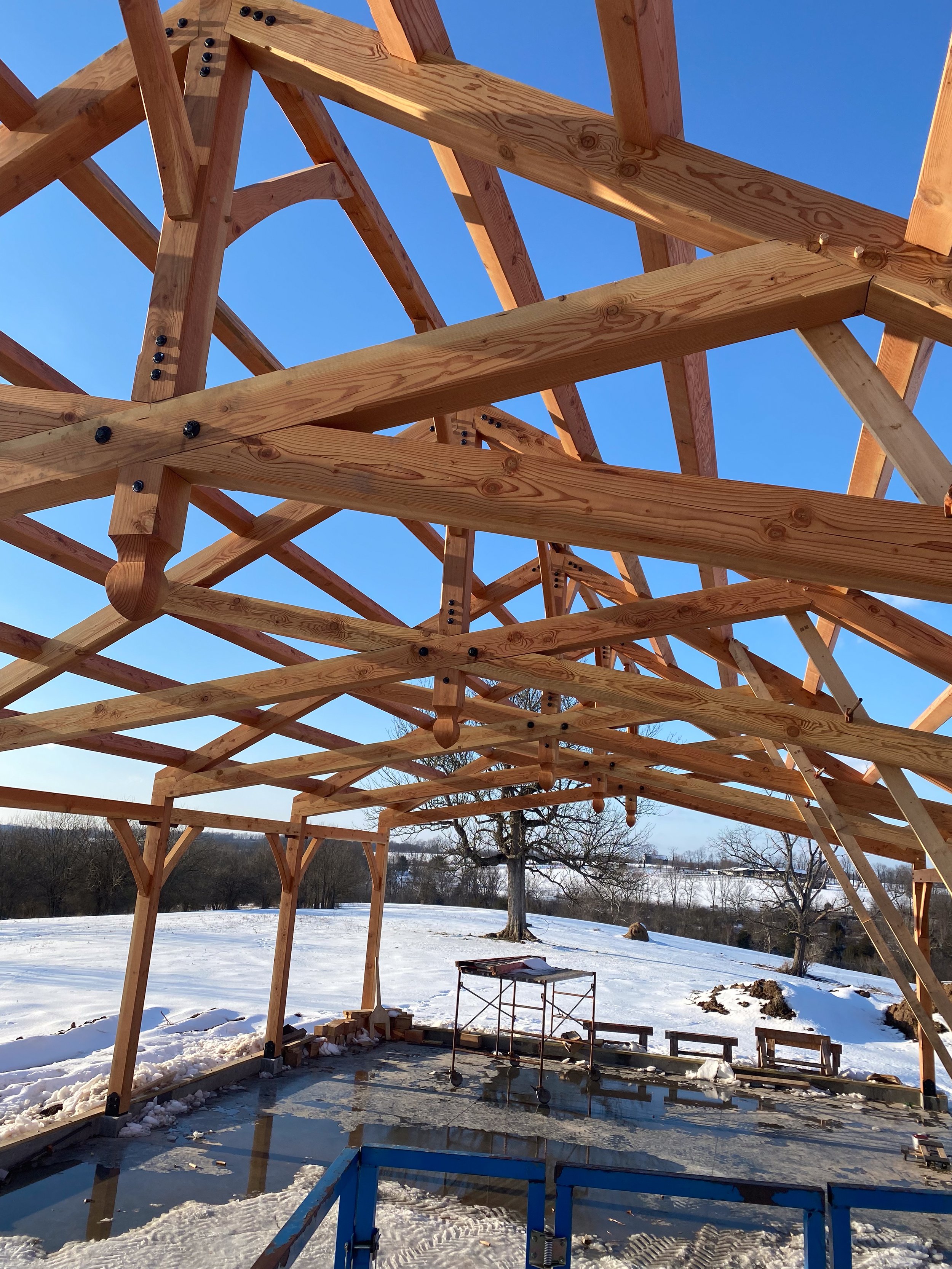Wooden structure under construction on a snowy landscape with a clear blue sky.
