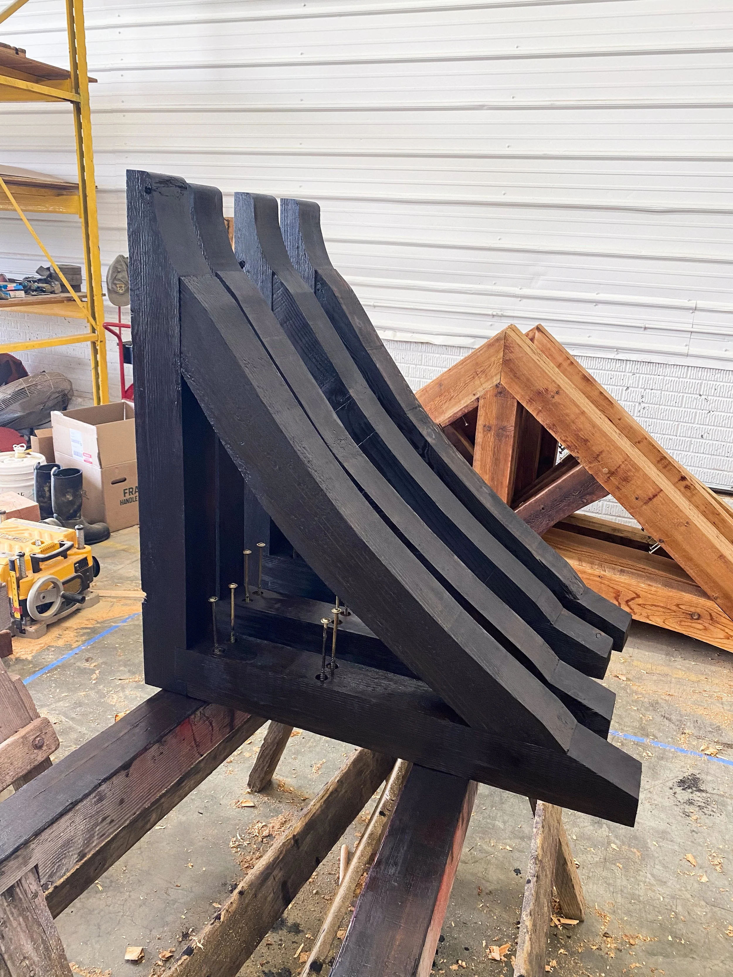Stack of black painted wooden beams on a workbench in a workshop.