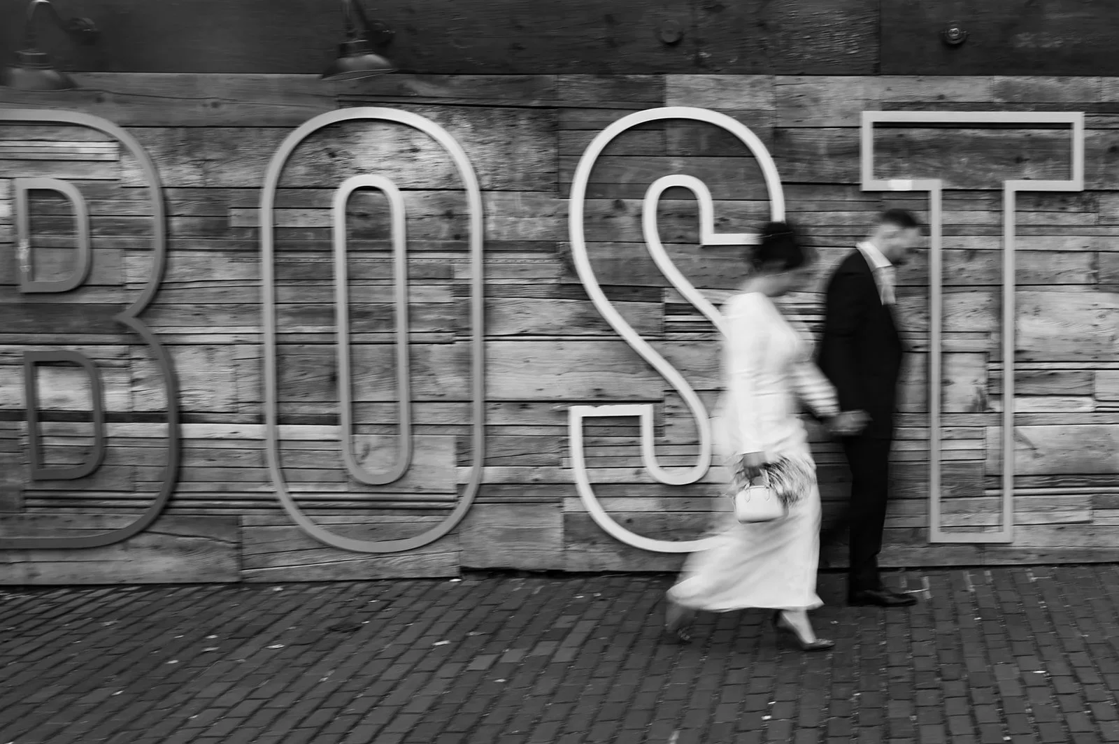 blurry image of couple walking in front of boston sign after eloping