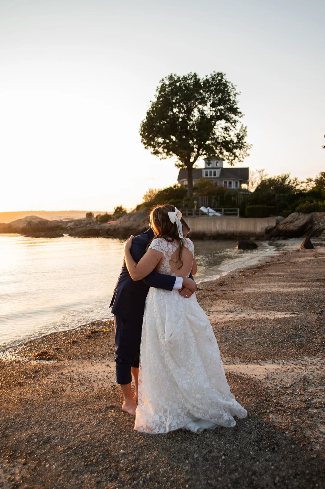 Bride and groom share a hug on Gloucester, MA beach at sunset.