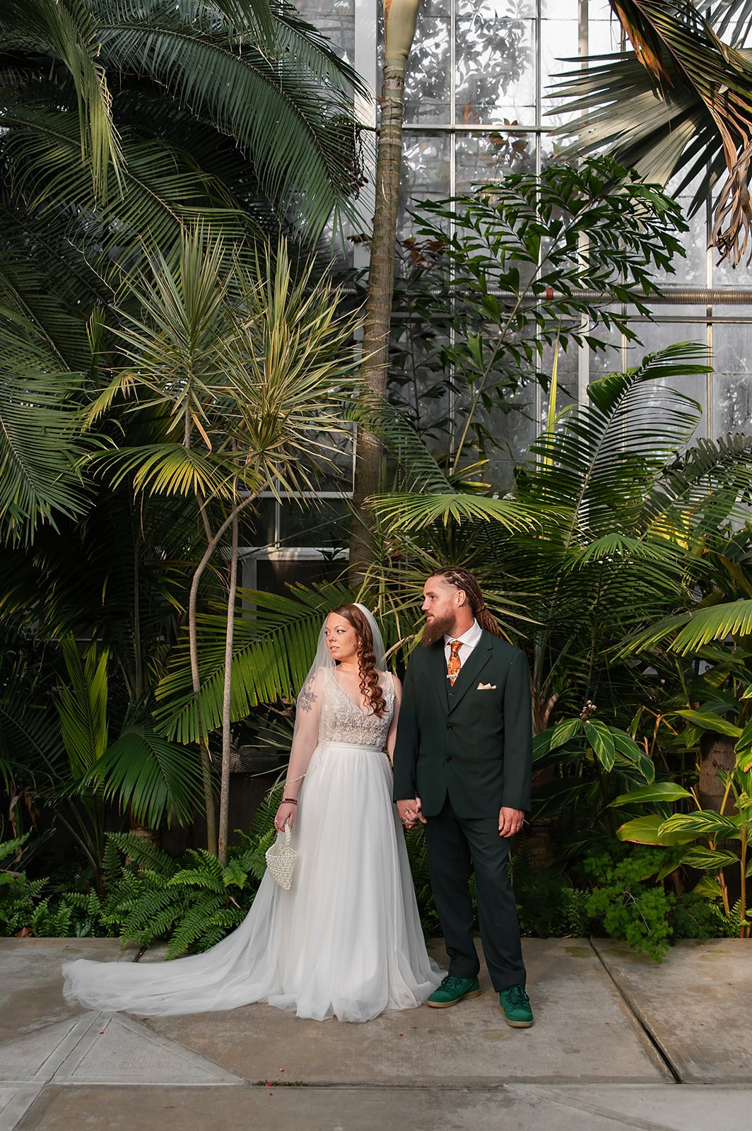bride and groom looking off at botanical garden