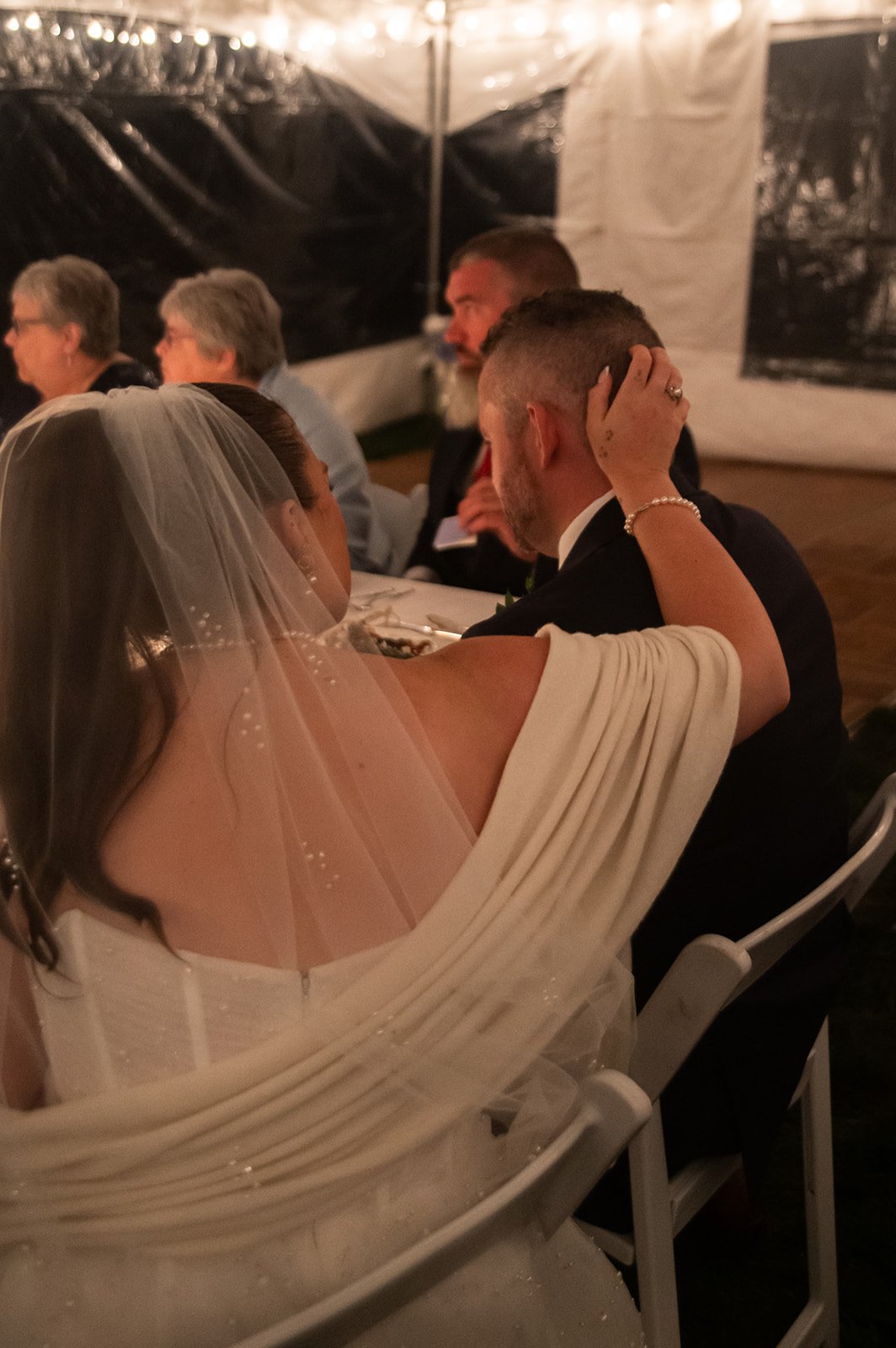 bride caressing groom's head during speeches