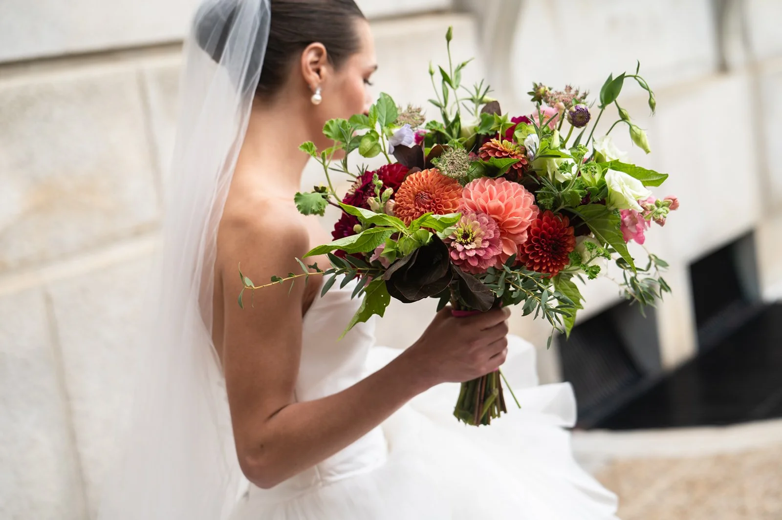 bride holding garden bouquet while walking up stairs at maine city hall wedding