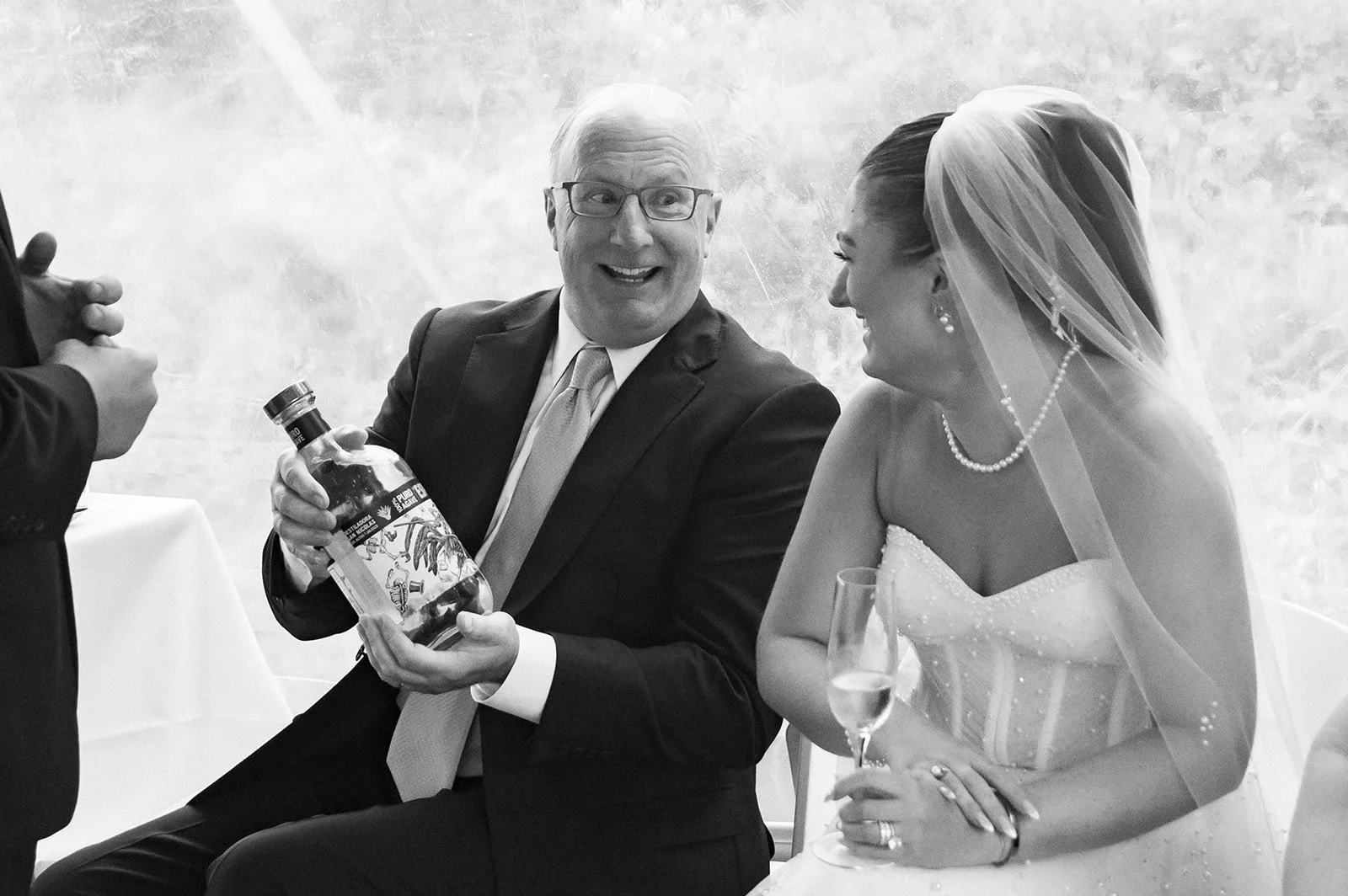 bride talking with dad holding bottle of tequila