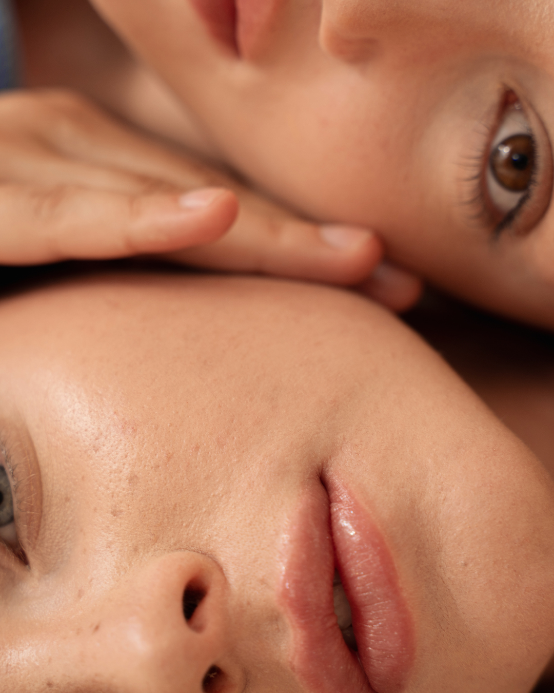 Close-up of two faces with a focus on lips and noses, lying down close to each other.