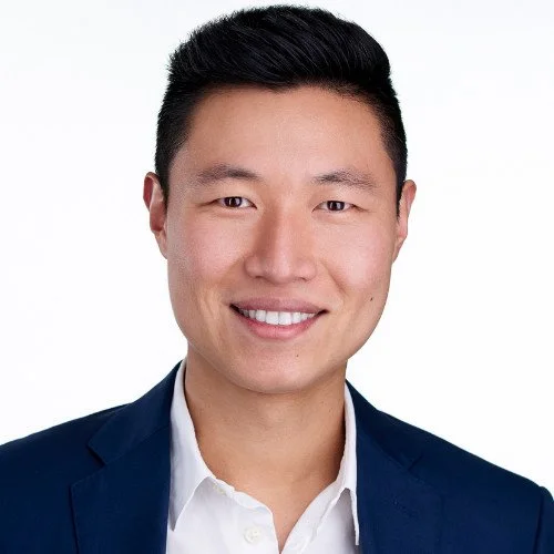 Portrait of a smiling man in a suit against a white background.