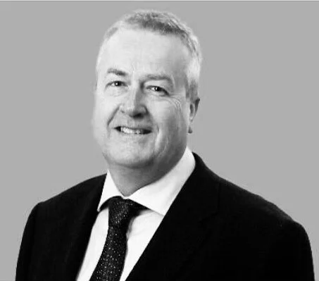 Black and white photo of a smiling man in a suit with a tie.