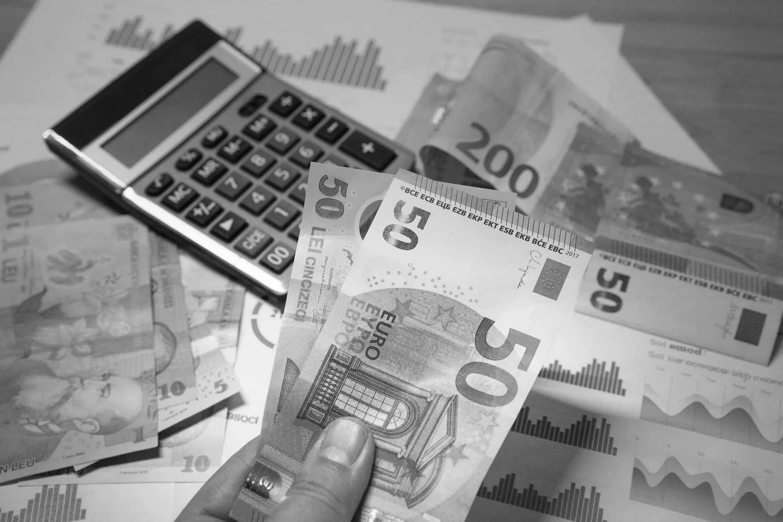 Euro banknotes, a calculator, and financial graphs on paper.