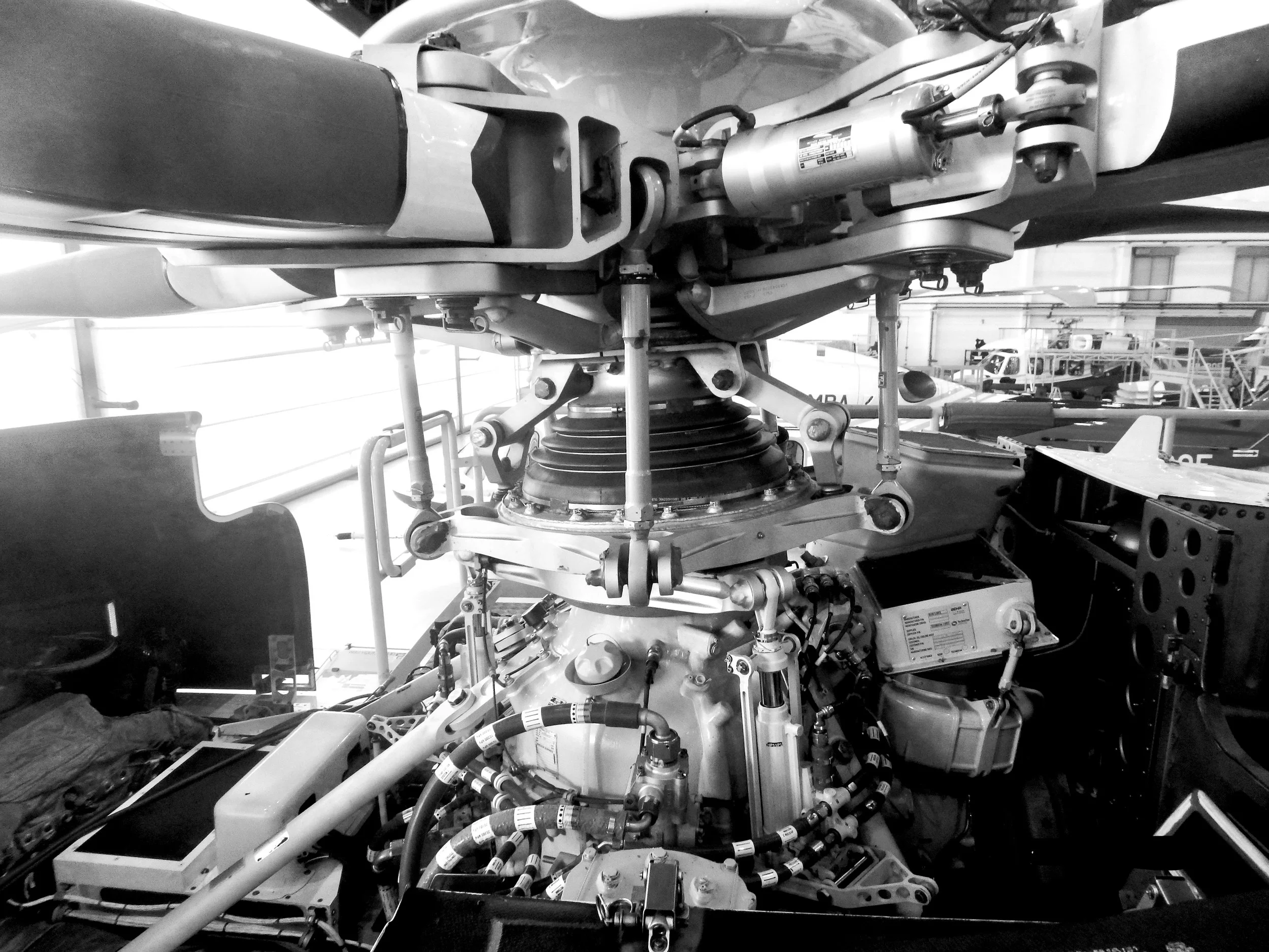 Close-up of helicopter engine and rotor mechanism in a hangar.