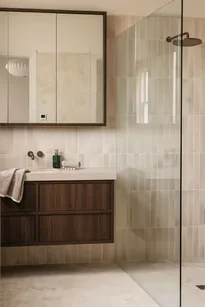 A minimalist bathroom with a dark wooden sink counters contrasted against pale beige tiles.