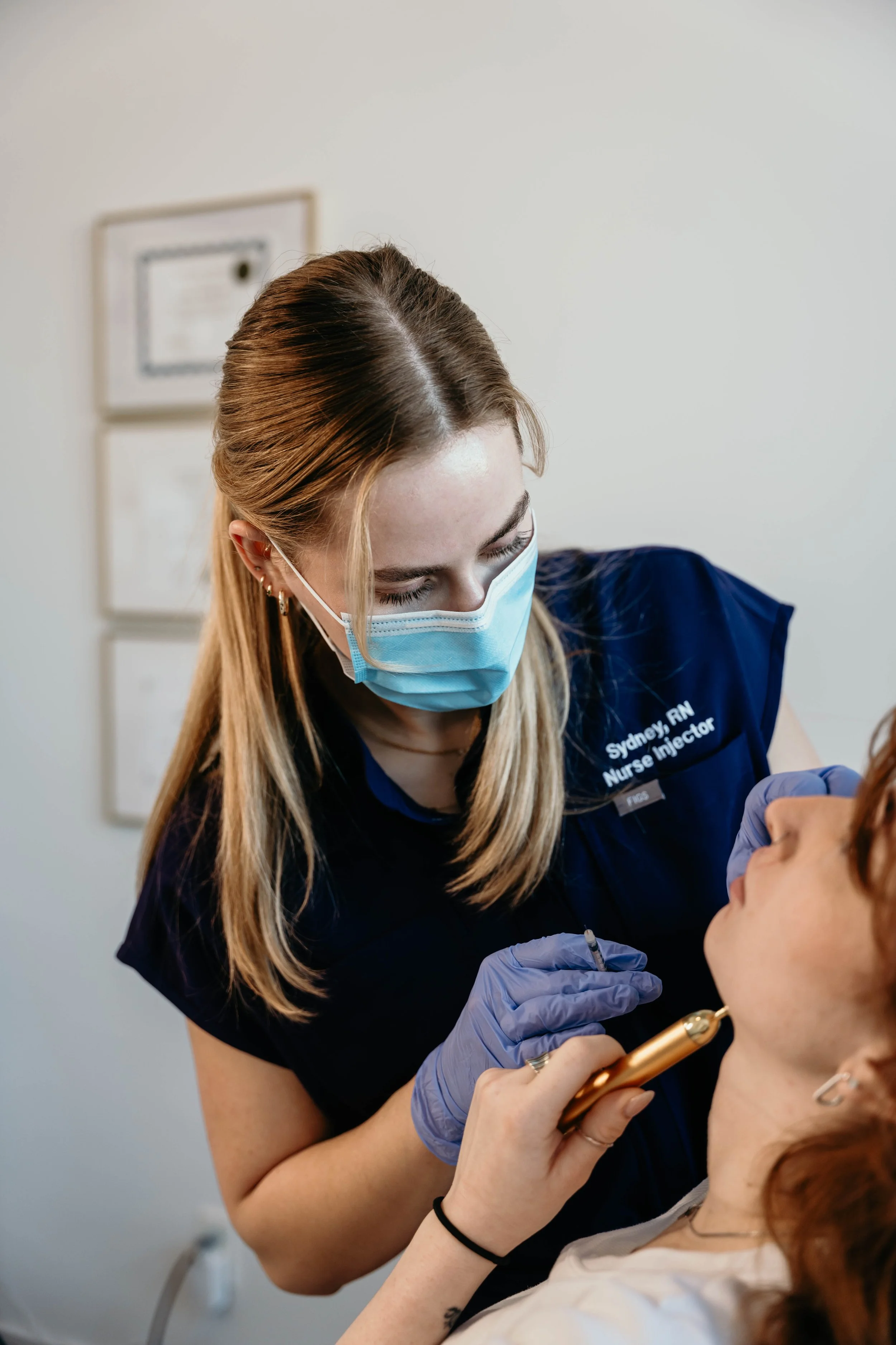 Nurse wearing a mask and gloves preparing a cosmetic injection for a patient.