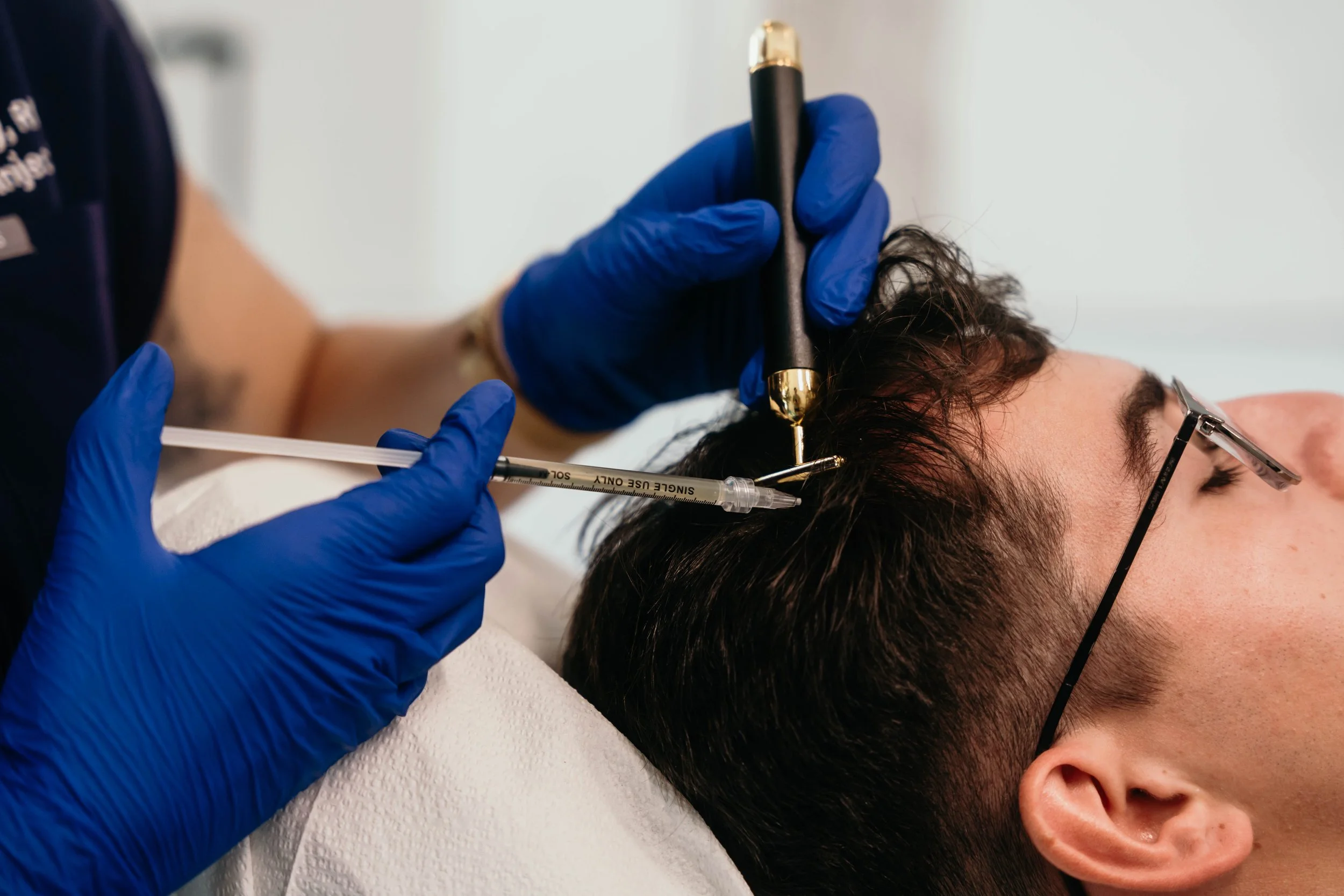 Person receiving scalp treatment with needle and handheld device