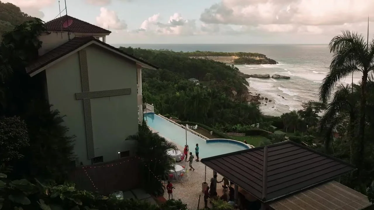 Aerial of the cliffside villa, infinity pool, and rocky Caribbean headland