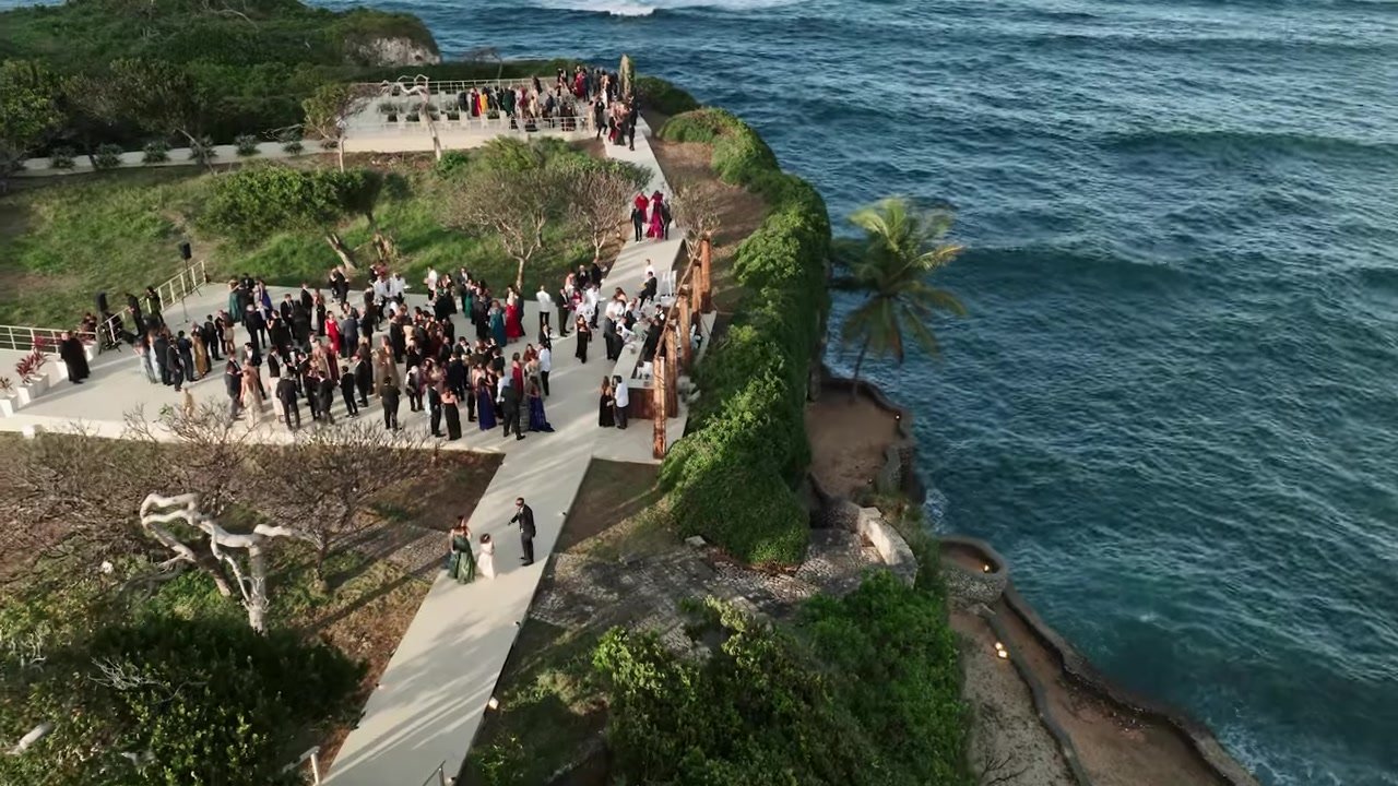Guests in formal clothes on white cliff terraces above deep blue water