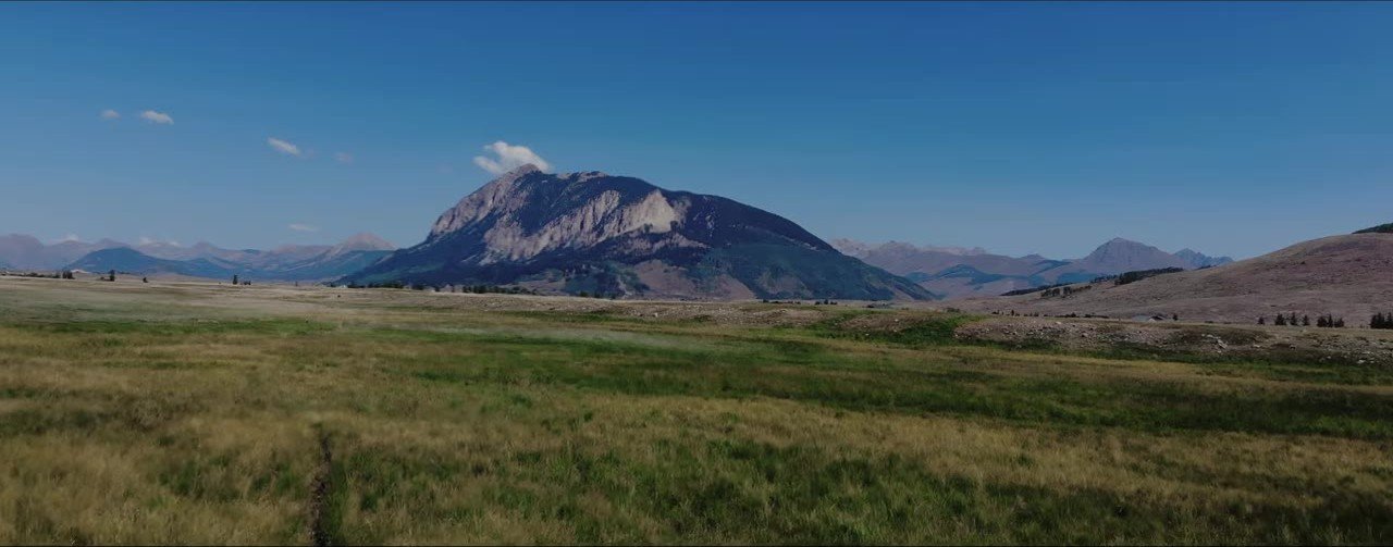 Crested Butte mountain peak and golden meadow under a deep blue sky